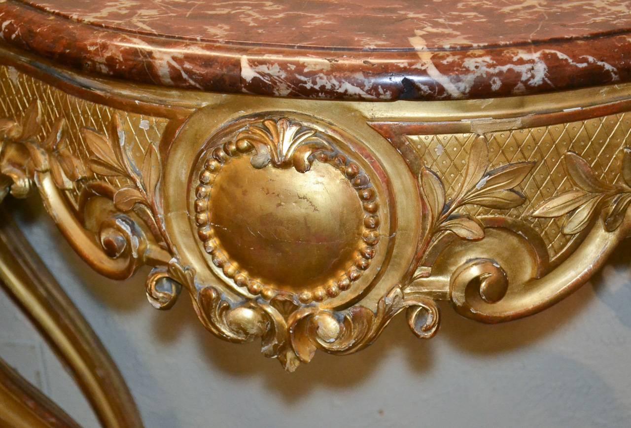 Fantastic 19th century French Louis XV giltwood console with lovely Griotte rouge de Belgique marble top. Having beautifully carved frieze accented in acanthus leaf motif, a lustrous gilt patina, and resting on graceful curved legs.