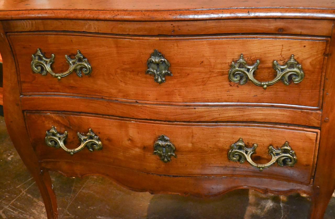 Splendid 18th century French Provincial walnut two-drawer commode. Having lovely bronze hardware in acanthus leaf motif, shaped front, and alluring rich warm patina. Wonderful for numerous designs!