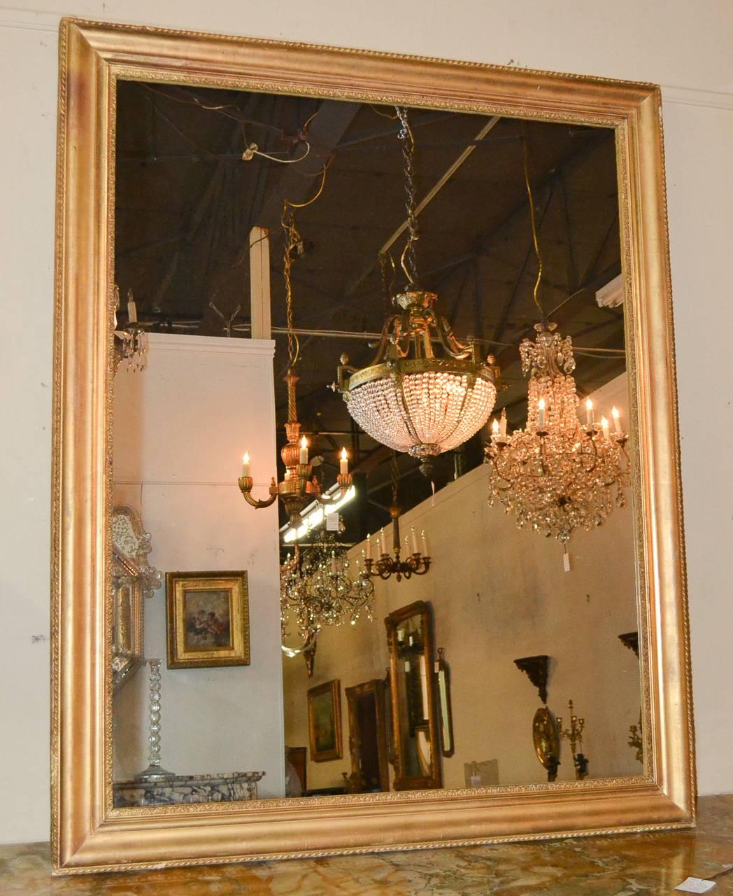 Alluring 19th century French over the mantel mirror. Having gorgeous water gilt finish, refined detailed trim, and of desirable size and proportion. Exhibiting clean lines that work in countless styles of decor!