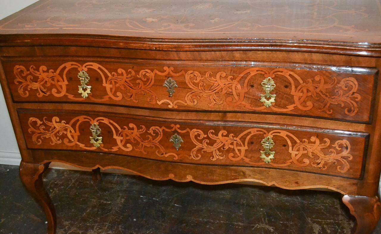Sensational 19th century Italian walnut two-drawer commode with marquetry inlays. Having beautiful and elaborate foliate and floral inlays on all sides, bronze hardware, and resting on cabriole legs. Exhibiting a rich warm patina that would