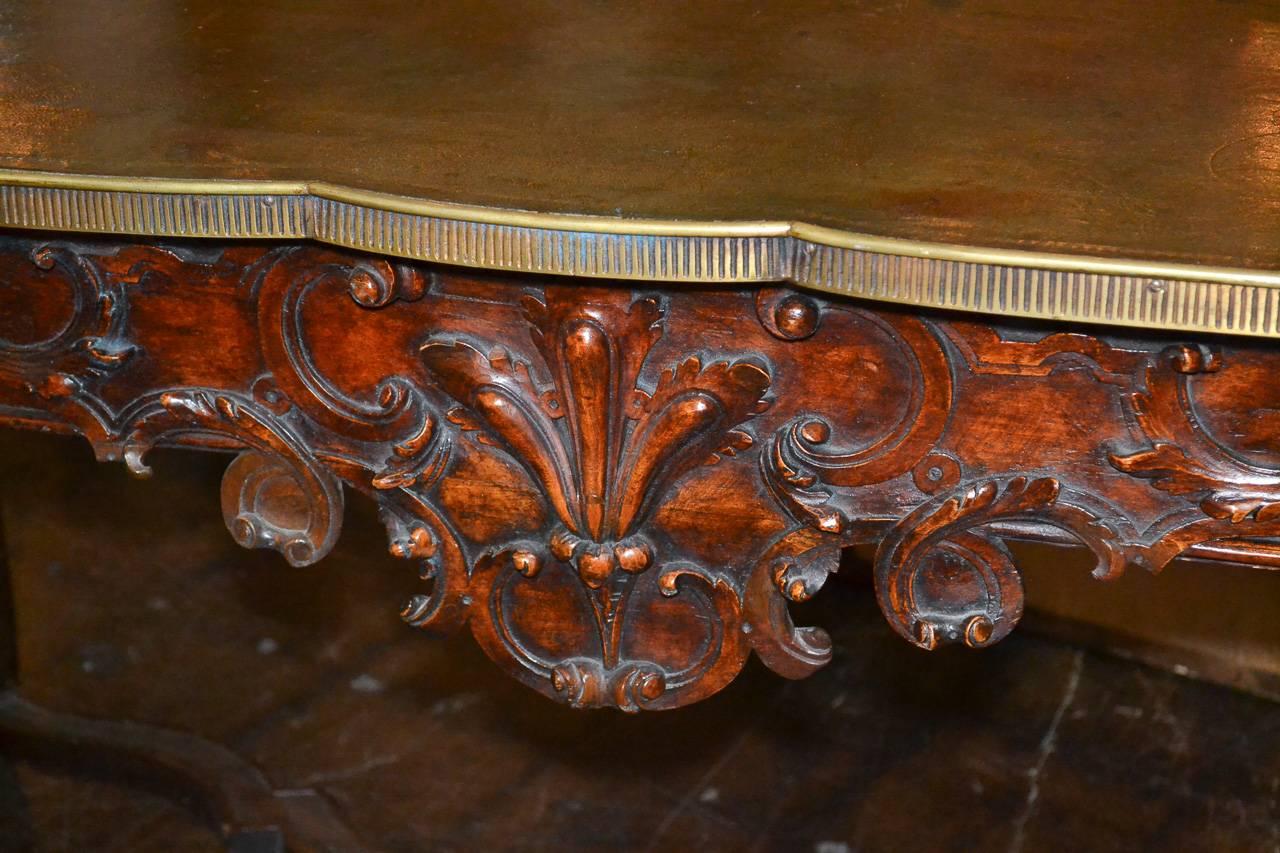 Marvelous 19th century, French walnut three-drawer writing table. Having lovely hand-carved apron and drawers in acanthus leaf motif, original tooled leather top, brass trim and carved x-stretcher. Wonderful for numerous designs.