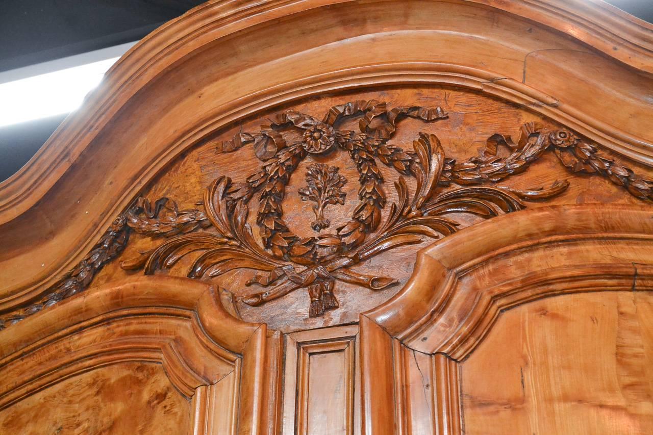 Outstanding 18th century French carved burl walnut four-door armoire from Lyon. Having excellent detailed carvings in wreath and laurel motif, beautifully shaped doors, heavy hardware, and resting on bunn feet. Exhibiting a stunning patina that