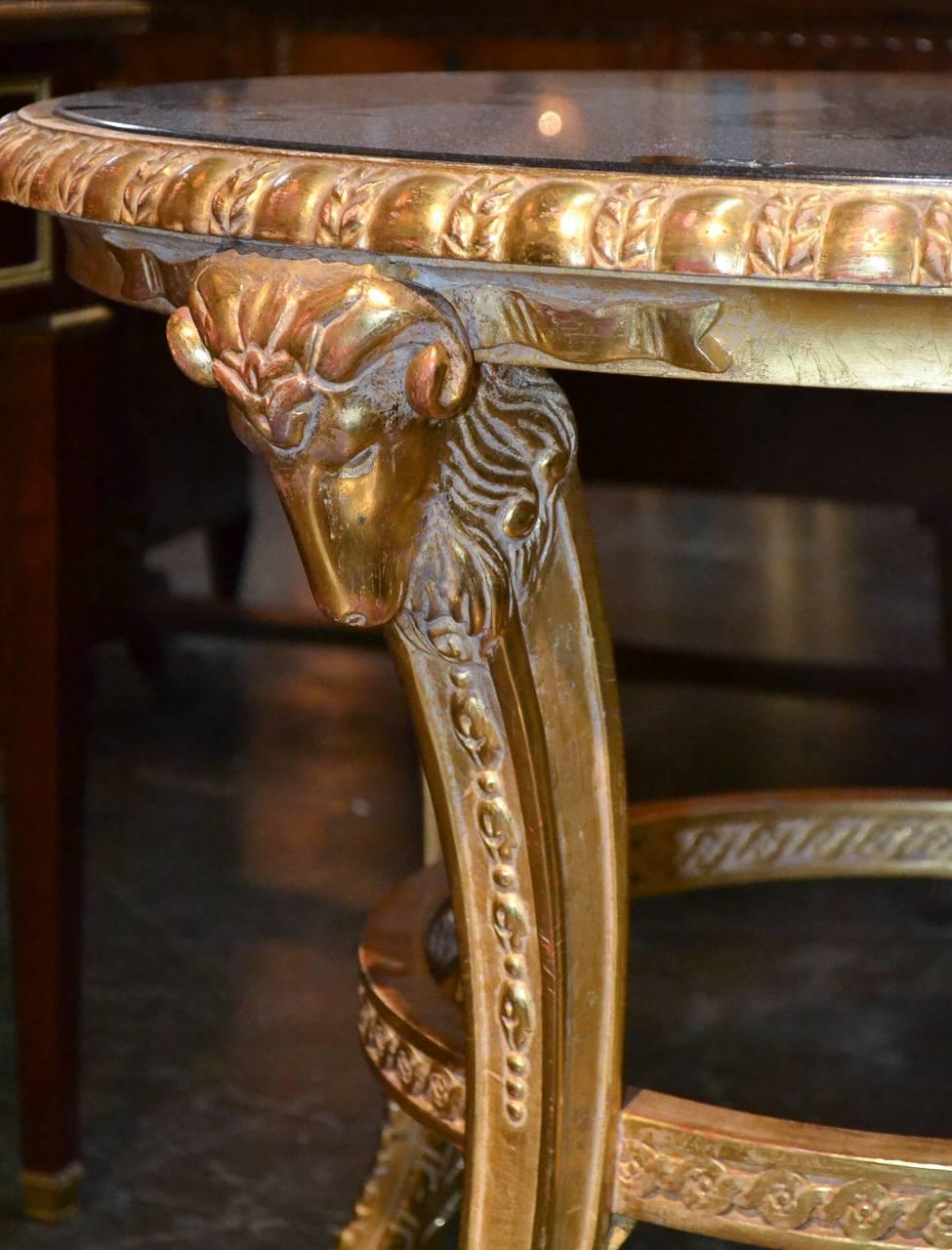 Sensational pair of French neoclassical carved giltwood side tables. Having lovely carved rams head legs terminating in cloven feet, matching black granite tops, and exhibiting beautiful lustrous patinas. Wonderful for numerous designs!