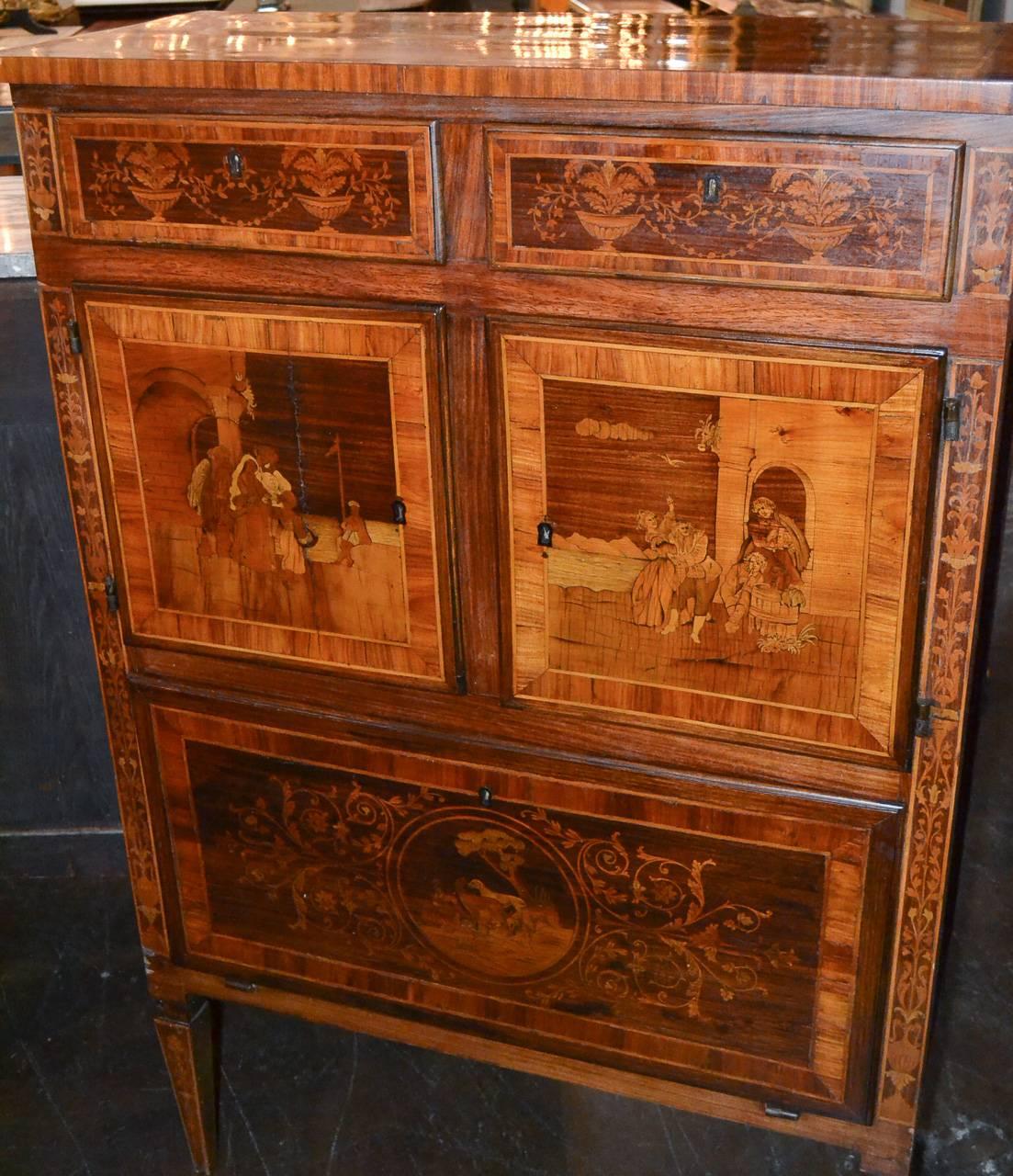 Splendid 19th century Italian Neoclassical cabinet with marquetry inlays.  Having wonderful inlaid figural scenes on doors and top, lovely marquetry motif overall, and resting on tapered legs.  Featuring clean lines and beautiful patina that would
