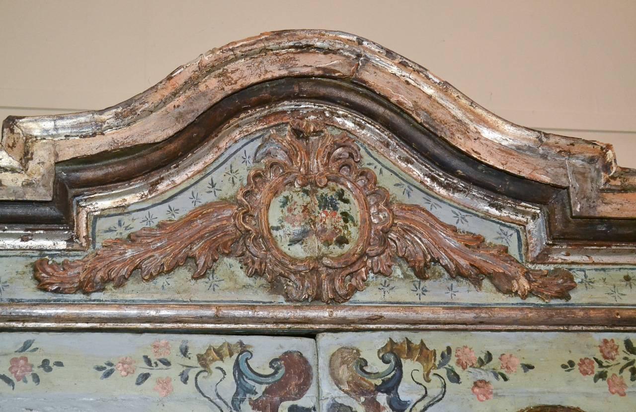 Beautiful 18th century Italian painted and polychromed 4-door, 1-drawer cabinet. Having lovely painted front in colourful floral motif, pediment with carved acanthus leaf accent, and exhibiting a charming aged patina.  Fabulous for numerous designs!