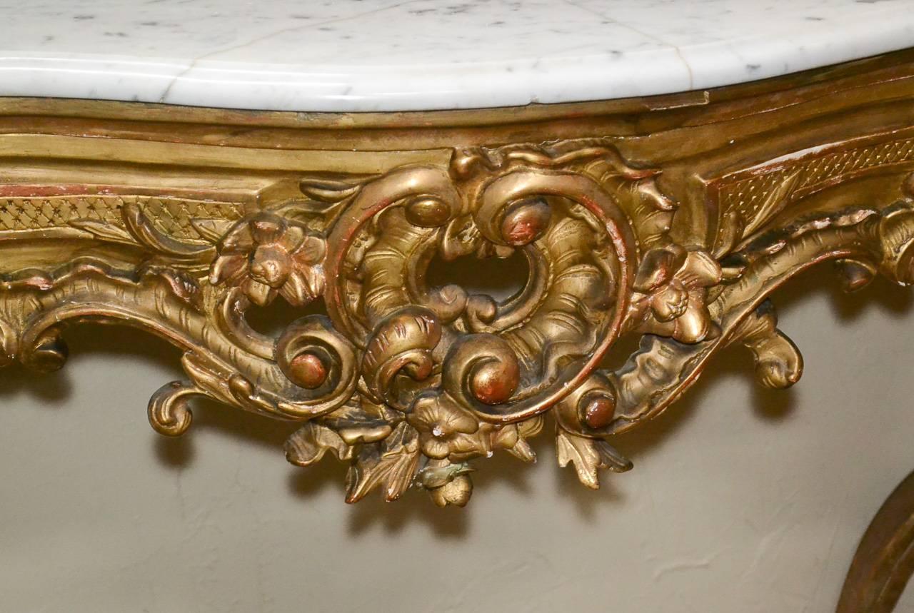 Stunning 19th century French Louis XV Rococo carved giltwood console. Having beautifully carved giltwood frame in acanthus leaf motif, thick Carrara marble top, and exhibiting a lustrous aged gilt patina. Beyond chic for numerous designs!
 
