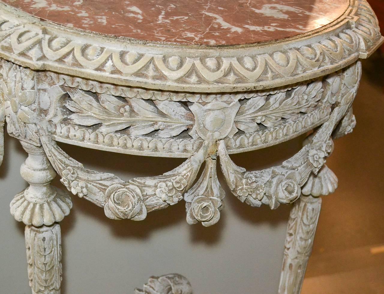 Delightful 19th century pair of French Louis XVI carved and painted consoles. Having wonderfully carved frames with reticulated aprons, swag, urn and floral stretchers, fluted tapered legs, and lovely incarnate turquin marble tops. Ready for your