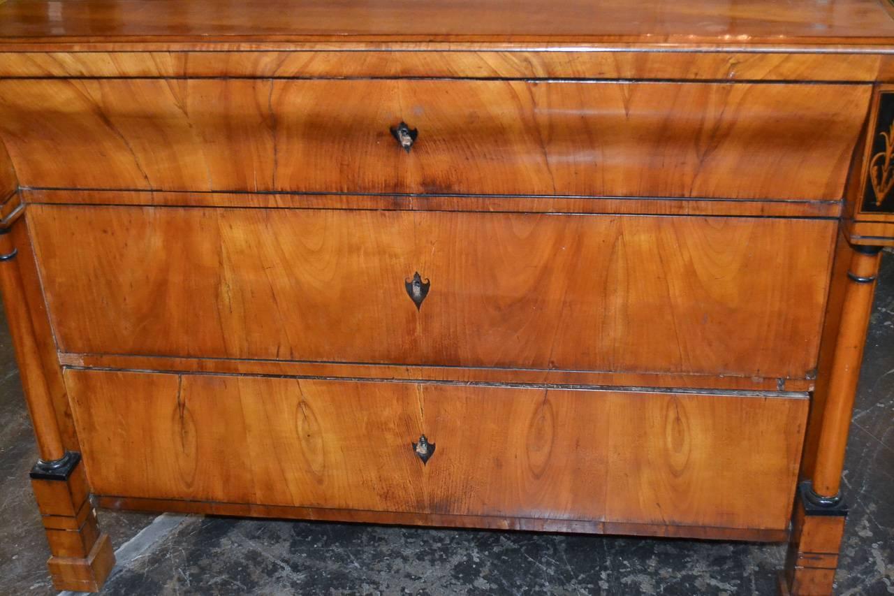 Exquisite 19th century Austrian Biedermeier fruitwood three-drawer commode. Having stylish ebonized detailing, turned columnar supports, and a gorgeous aged warm patina. Featuring clean lines that work in countless styles of decor.