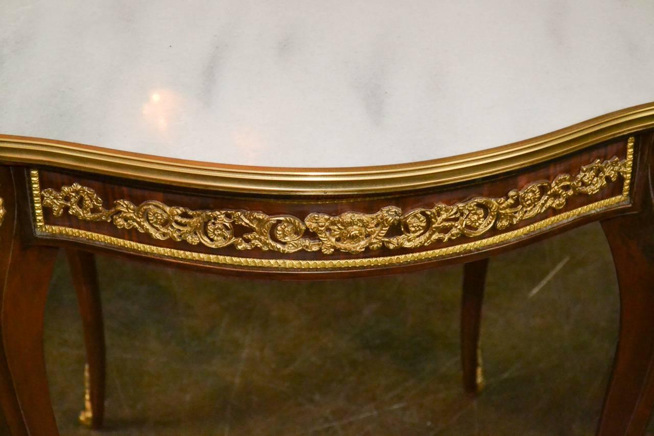 Splendid pair of French mahogany side tables with Carrara marble tops. Having lovely gilt bronze mounts in acanthus leaf motif, exhibiting a rich warm patina, and resting on gracefully tapered legs. Wonderful for numerous designs!