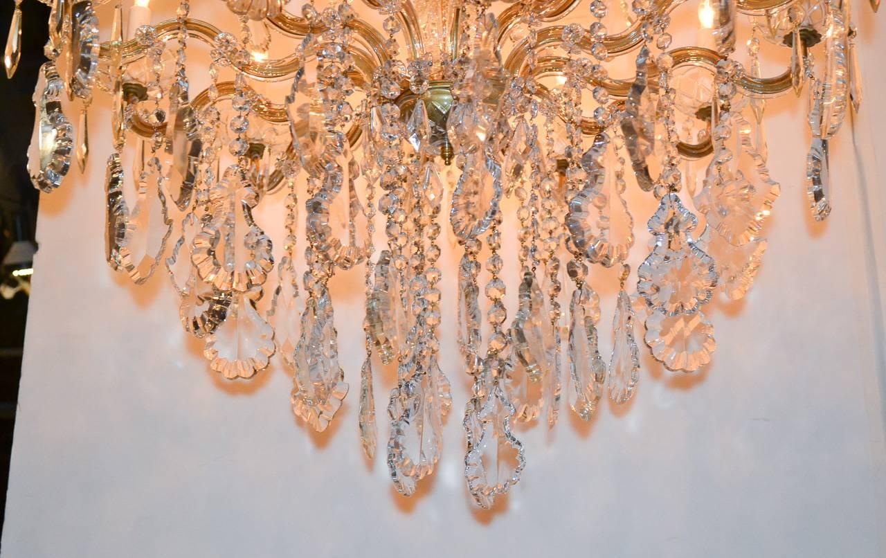 Marvelous French Maria Theresa 18-light crystal chandelier.  Having impressive cut crystal center column, elegant waving arms, and beautifully adorned with large pendeloque crystal prisms.  Wonderful for numerous designs!