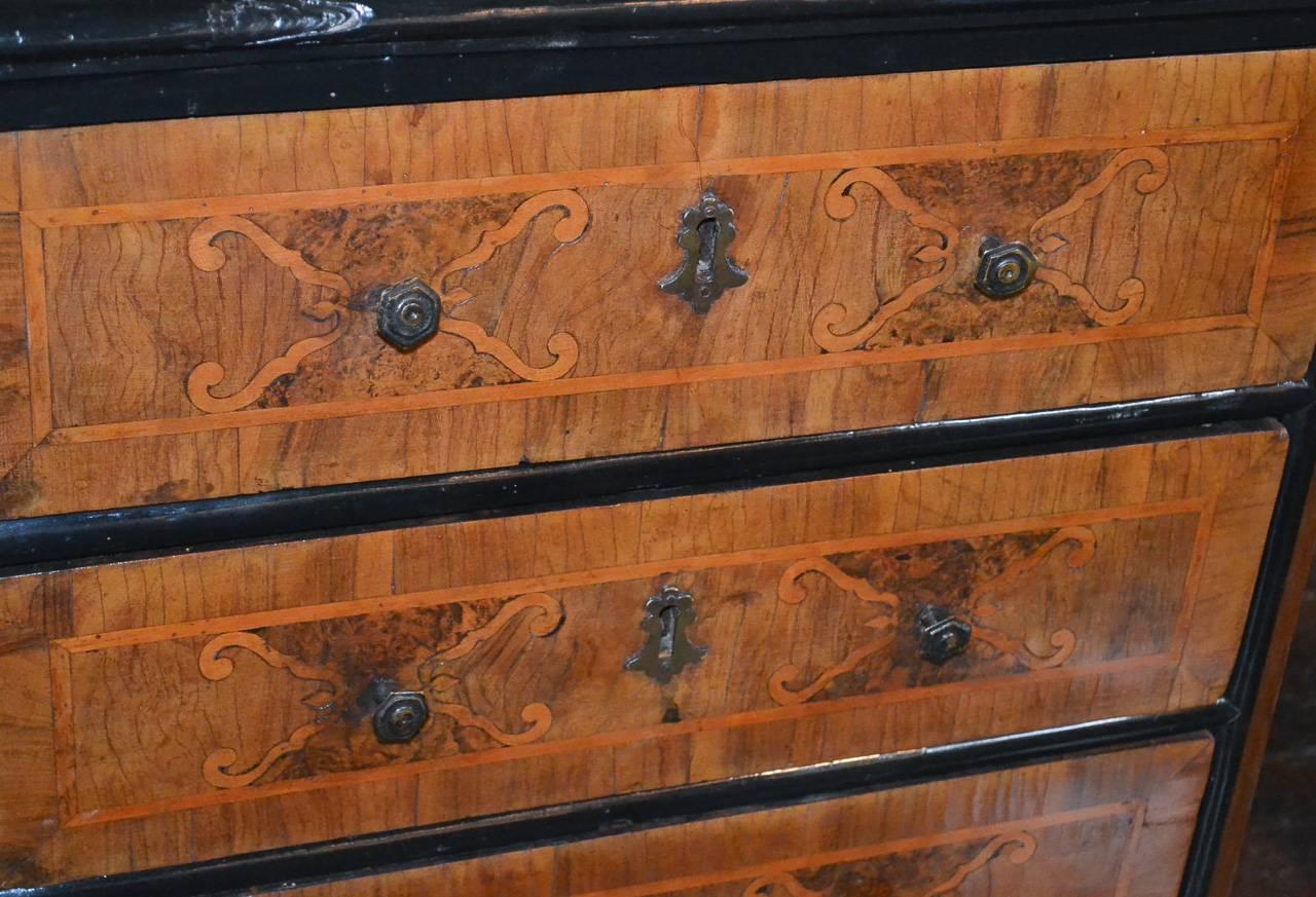Sensational 18th century south German walnut four-drawer chest. Having lovely delicate inlays on all sides, wonderfully aged bronze hardware, and striking ebonized trim. Fabulous for numerous designs!