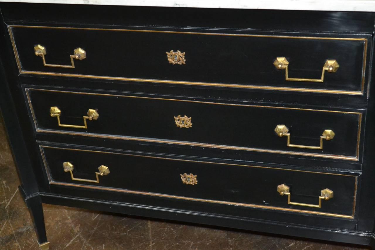 Excellent French midcentury Jansen style three-drawer commode. Having gilt bronze hardware, Carrara marble top, and fantastic black lacquered finish. Featuring stylish straight lines perfect for many types of decor!