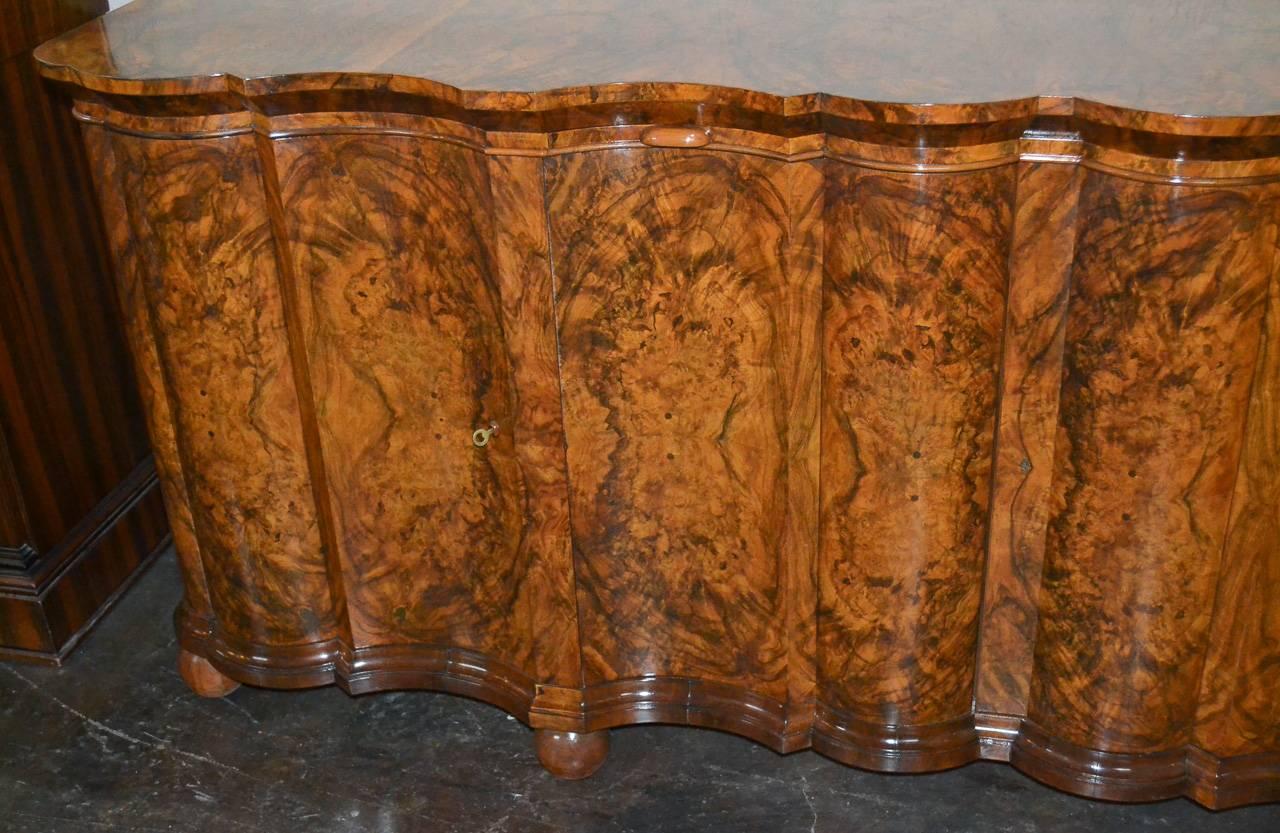 Excellent Italian burl walnut four-door sideboard. Having beautiful shaped Front Design, wonderful patina, and resting on ball feet. Exhibiting a gorgeous finish perfect for many designs!