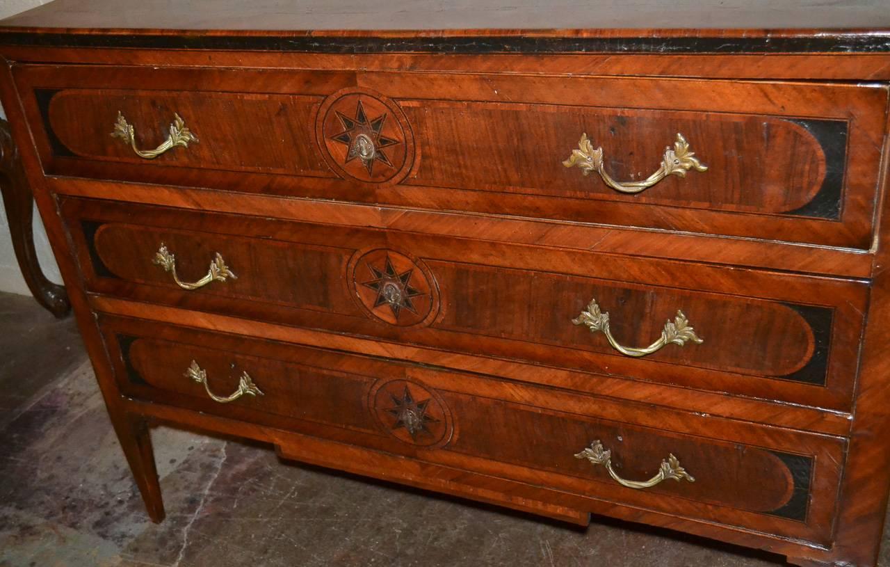 Incredible 18th century Northern Italian walnut three-drawer commode. Having wonderful geometric inlays on all sides, gilt bronze hardware in acanthus leaf motif, and stylish ebonized detailing. Showcasing a beautifully aged patina and clean lines