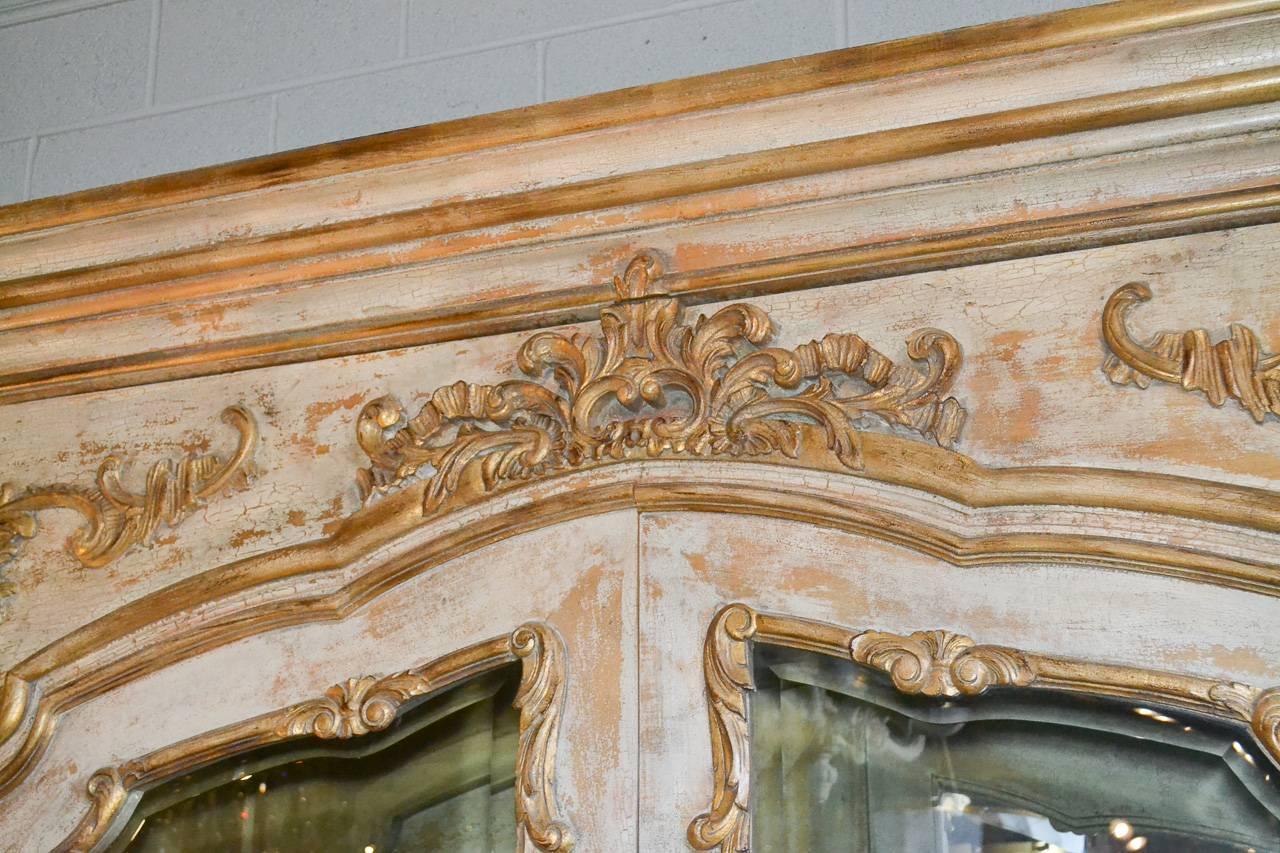 Gorgeous and impressive Italian parcel-gilt, two-door display cabinet. Having large acanthus leaf motif carvings, beveled glass in doors, mirrored interior, and wonderful painted and parcel-gilt finish. Perfect for today's stylish decors!