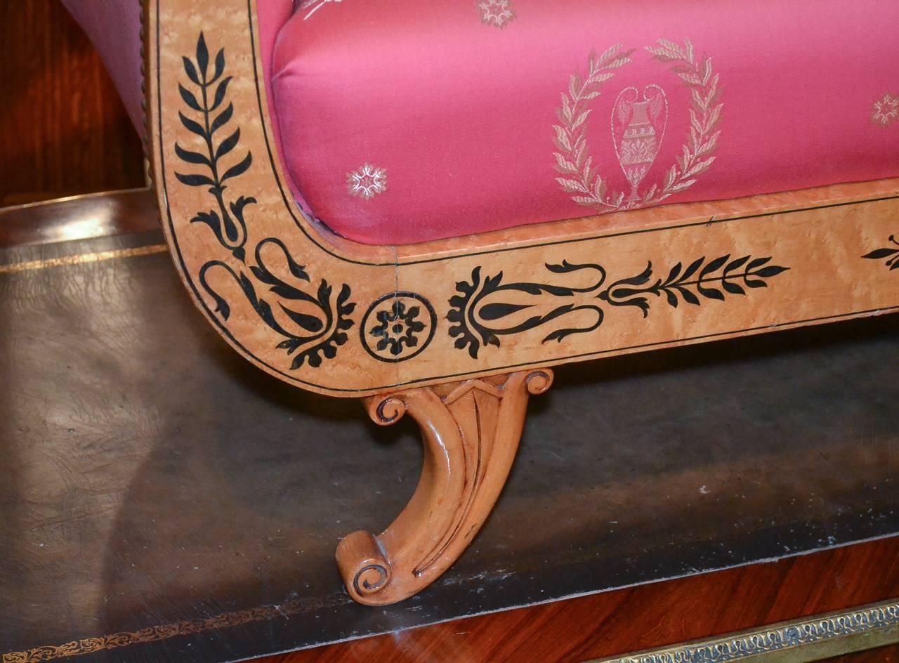 Fantastic Austrian Biedermeier maple settee, circa 1880. Having lovely ebony foliate inlays against a warm beautiful finish. Upholstered in vibrant red fabric with wreath and urn motif, and having gracefully curved lines.