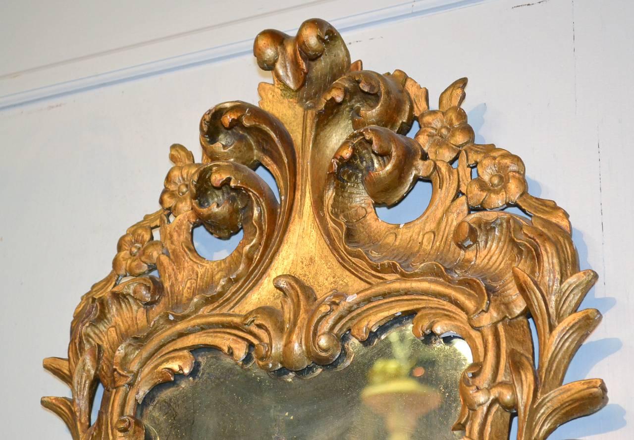 Splendid 19th century hand-carved Italian giltwood mirror, circa 1870. In baroque style with lustrous gilt finish and aged mirrored glass. 