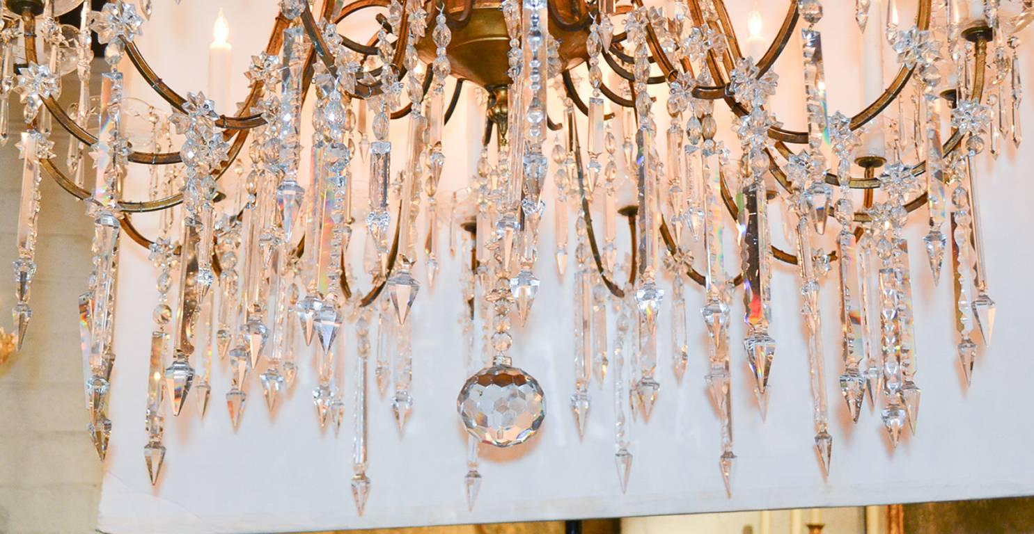 Stunning 19th century Italian giltwood and crystal suxteen-light chandelier. Having wonderful carved giltwood central column, gracefully curved arms, and adorned with spear prisms. 
                                