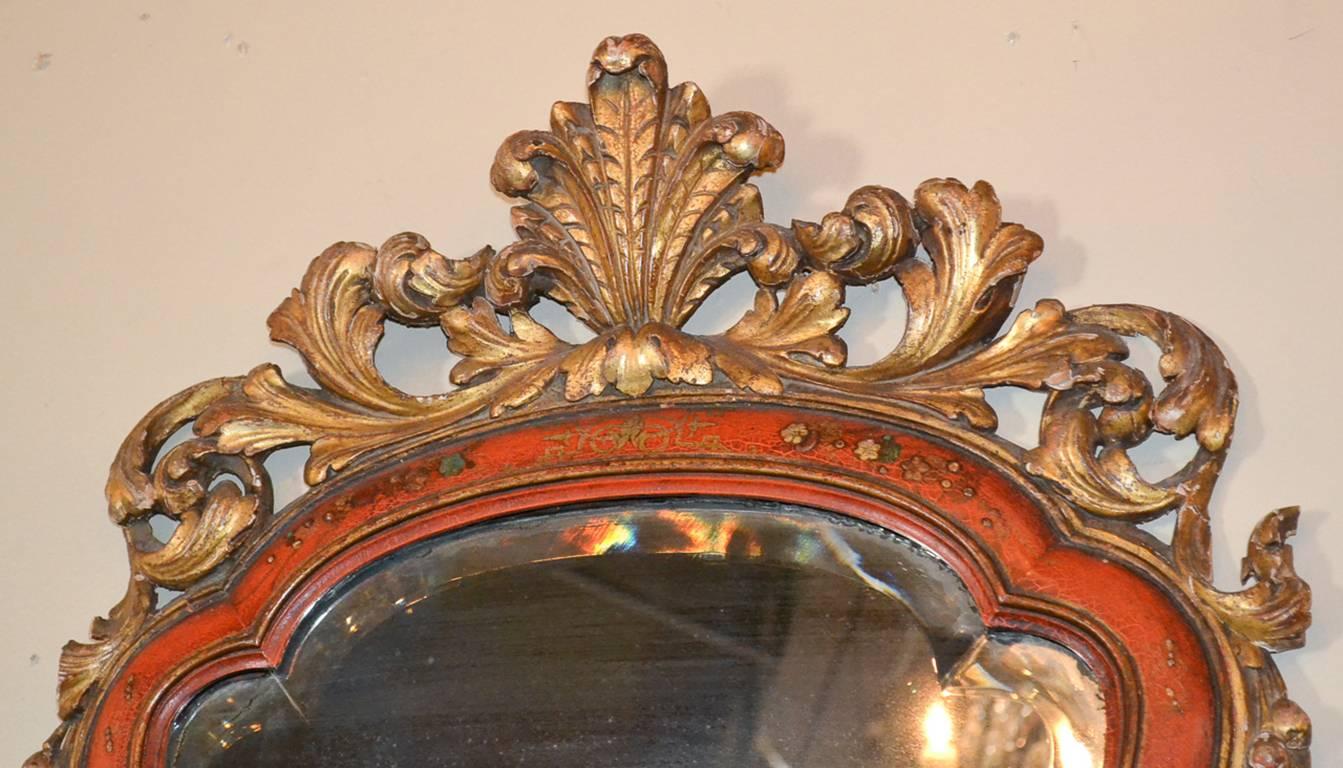 Rare 18th century English Queen Anne chinoiserie mirror. Having beautiful red lacquer and parcel-gilt finish, lovely carved cartouche, and unique scalloped beveled mirrored glass. Fabulous for numerous designs!