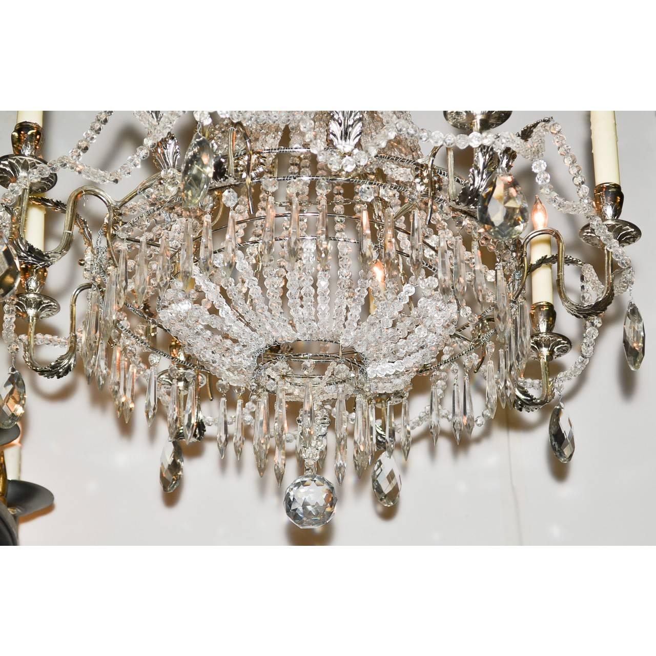 Elegant early 20th century French silver gilt, crystal and bronze chandelier. The canopy with leaf spray adornments draped with beaded crystal and large tear-drop crystal prisms. The main body with long strands of beaded crystal that form a small