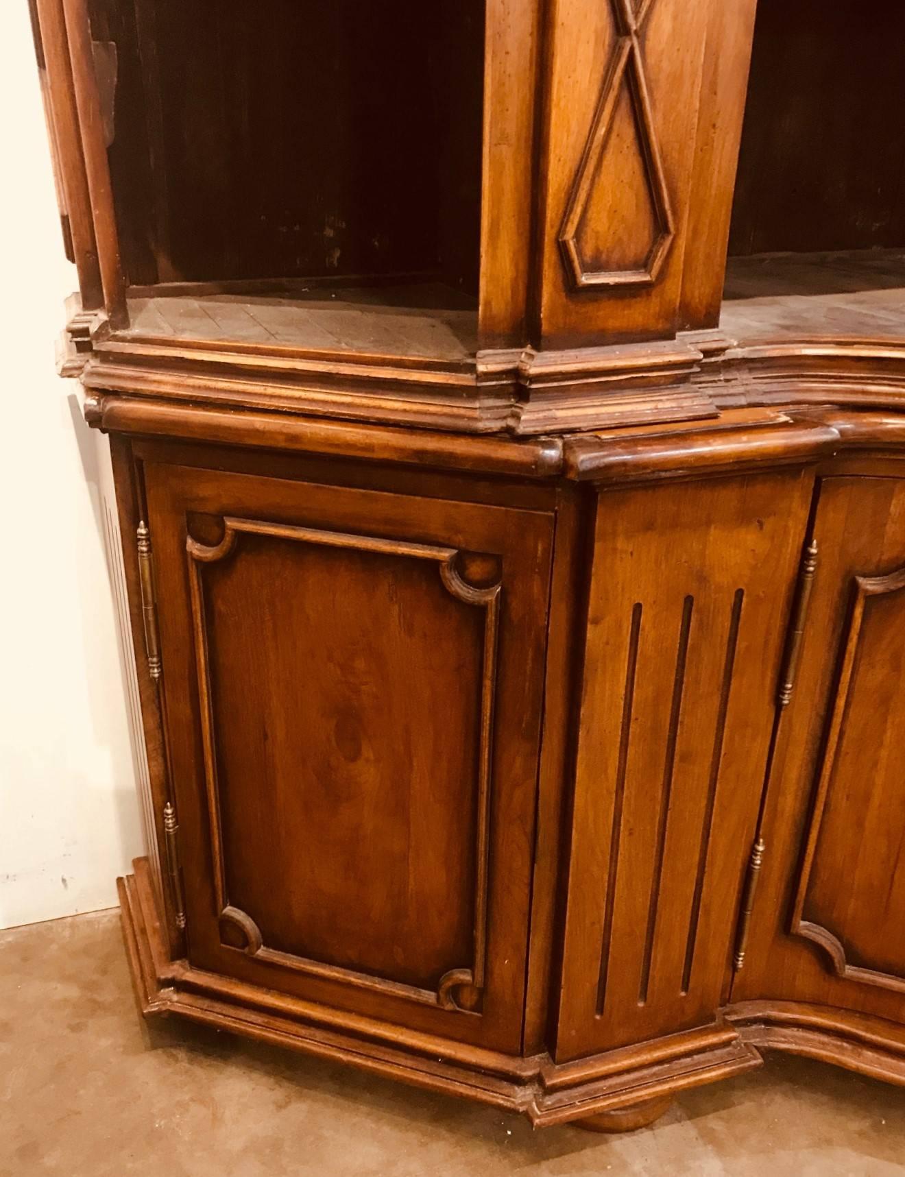 Impressive large custom crafted Italian Tuscan style walnut bookcase cabinet.

The beautifully shaped and contoured cornice above open shelving and facings with diamond shaped trim and shell and leaf carved accents. The shaped lower section with