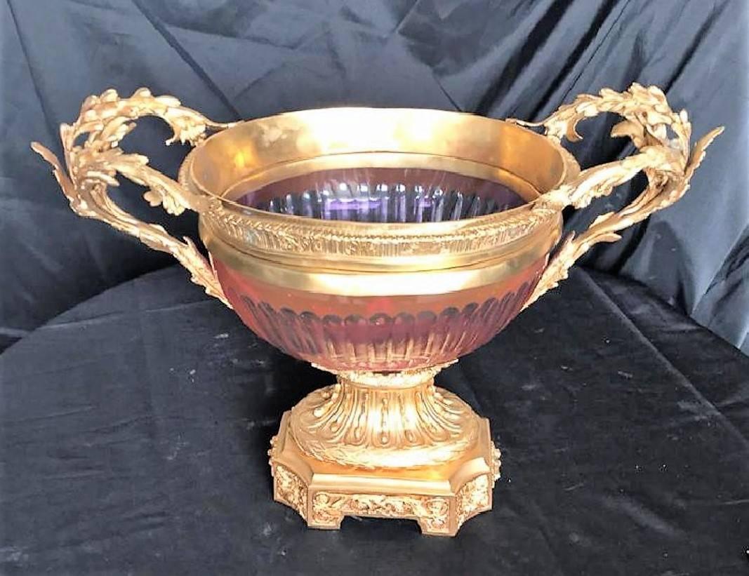 Exquisite vintage French gold-gilded bronze and cranberry colored glass centrepiece with ornate leaf scroll handles. The fluted bowl encased in doré bronze with stylized rim.

The bronze base with a thistle motif atop a shaped plinth with foliate