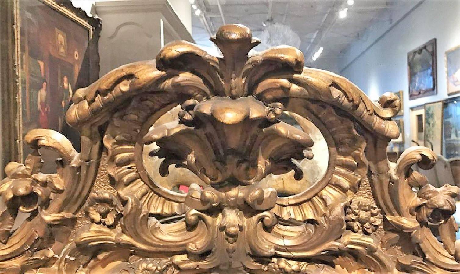 Finely carved 19th century French Napoleon III giltwood and gesso oval wall mirror. 

The pediment carved with large leaf scrolls and small garlands atop a superbly carved ribbon and flower head motif border.

Has original mirror and original