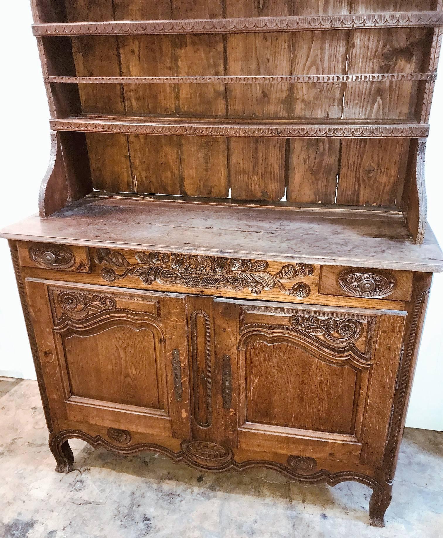 Exceptional 18th century French oak vaisselier, dresser, or buffet from Provence.

The top portion with a carved cornice atop open plate racks. The frieze with fine recessed carvings of scrolling flower vines and flower heads, and fitted with two
