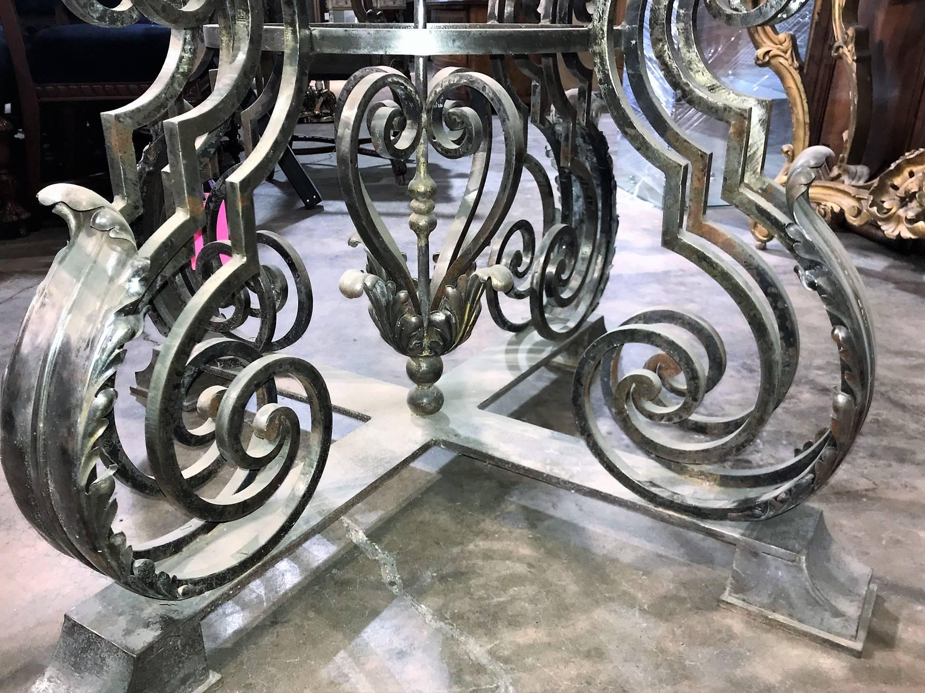 Remarkable and large custom-made French styled polished iron center table with silver-gilt patina. The top supported by massive C-shaped scrolled legs with bold acanthus leaf accents atop and X-form footed base.

The top extends to create a large