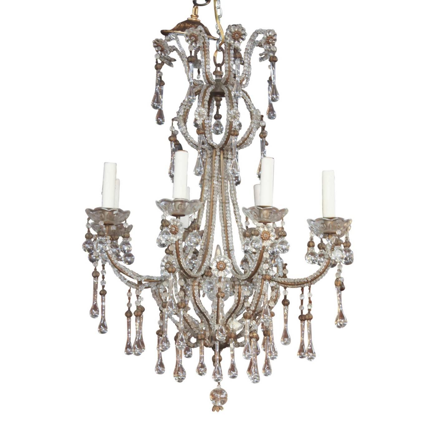 Gorgeous Italian crystal chandelier decorated overall with small cut crystal beads and accented with crystal rosettes. The gracefully curved arms end in scalloped candle cups. The lower most adorned with long tea-shaped crystal drops.