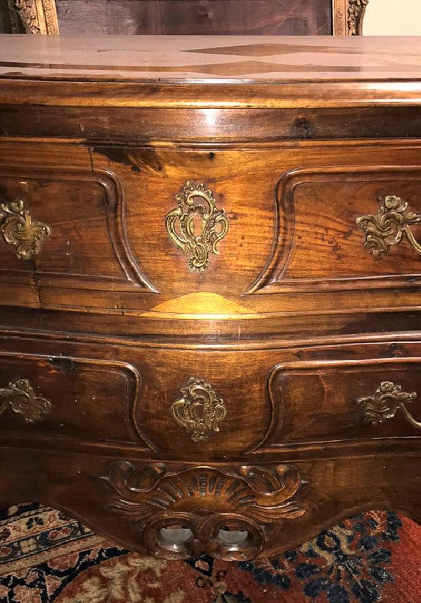 Superb early 19th century French Louis XV style hand-crafted walnut commode. The serpentine shaped top above two drawers with fancy bronze pulls and escutcheons. The carved shell motif skirt flows smoothly to cabriole form legs that terminate in a