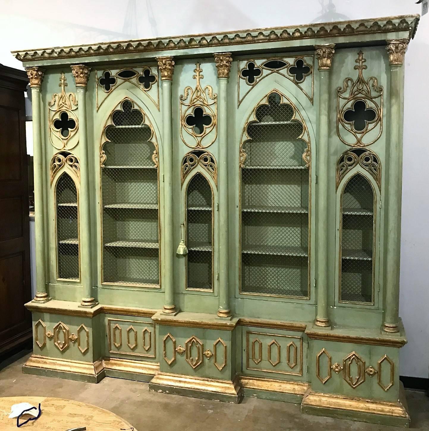 Particularly Fine late 19th century Italian Gothic Revival breakfront cabinet bookcase with parcel-gilt accents. The molded out-swept leaf carved cornice above Gothic arched shaped grilled doors with trefoil carvings divided and flanked by pilasters