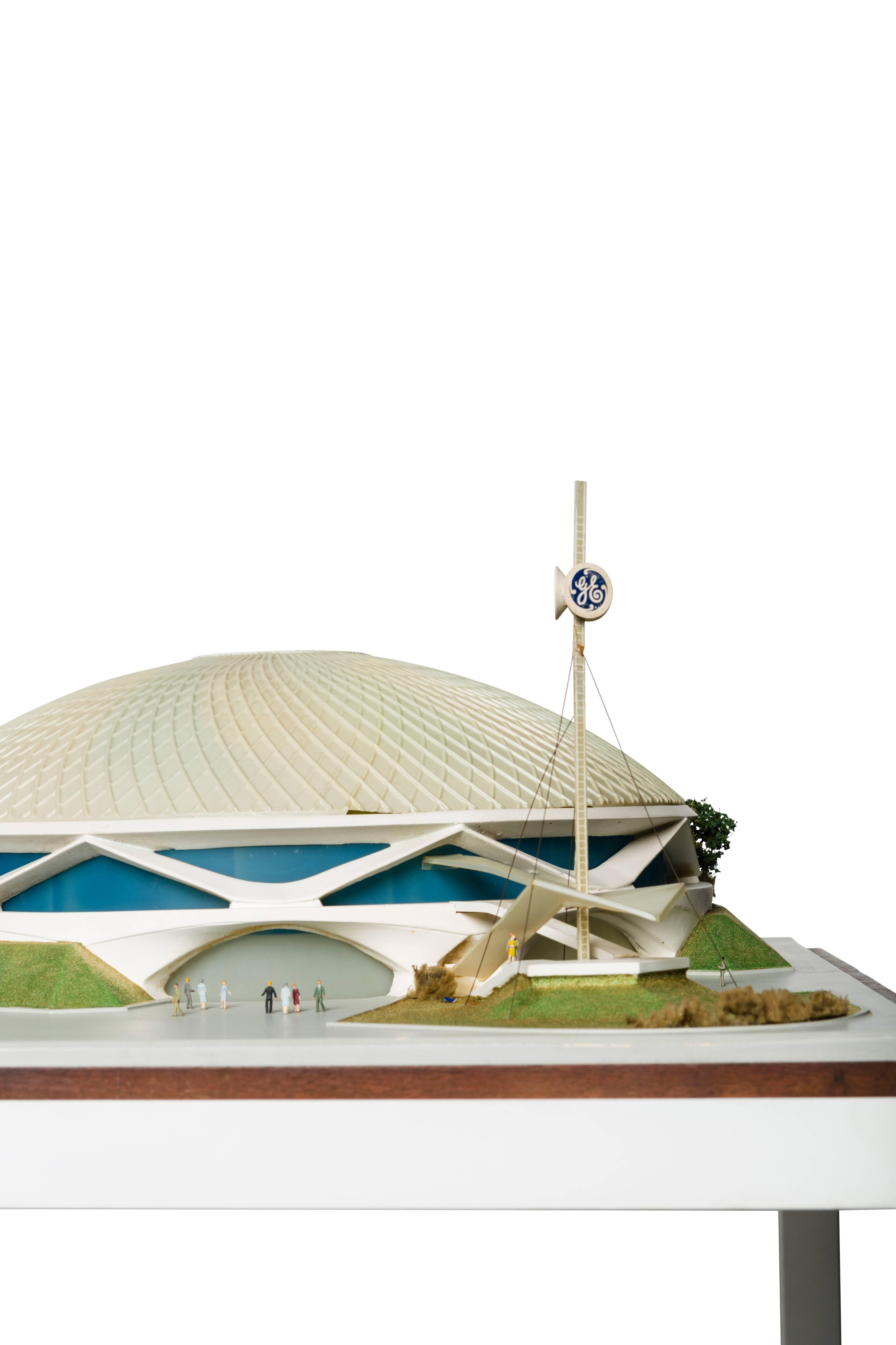 The scale model of “ Progressland” refers to the General Electric pavilion at the 1964 World’s Fair, whose themes were “ Progress through Electric Power” and “The Wonders of Atomic Energy.” In a brochure from the time, “Progressland” is described as