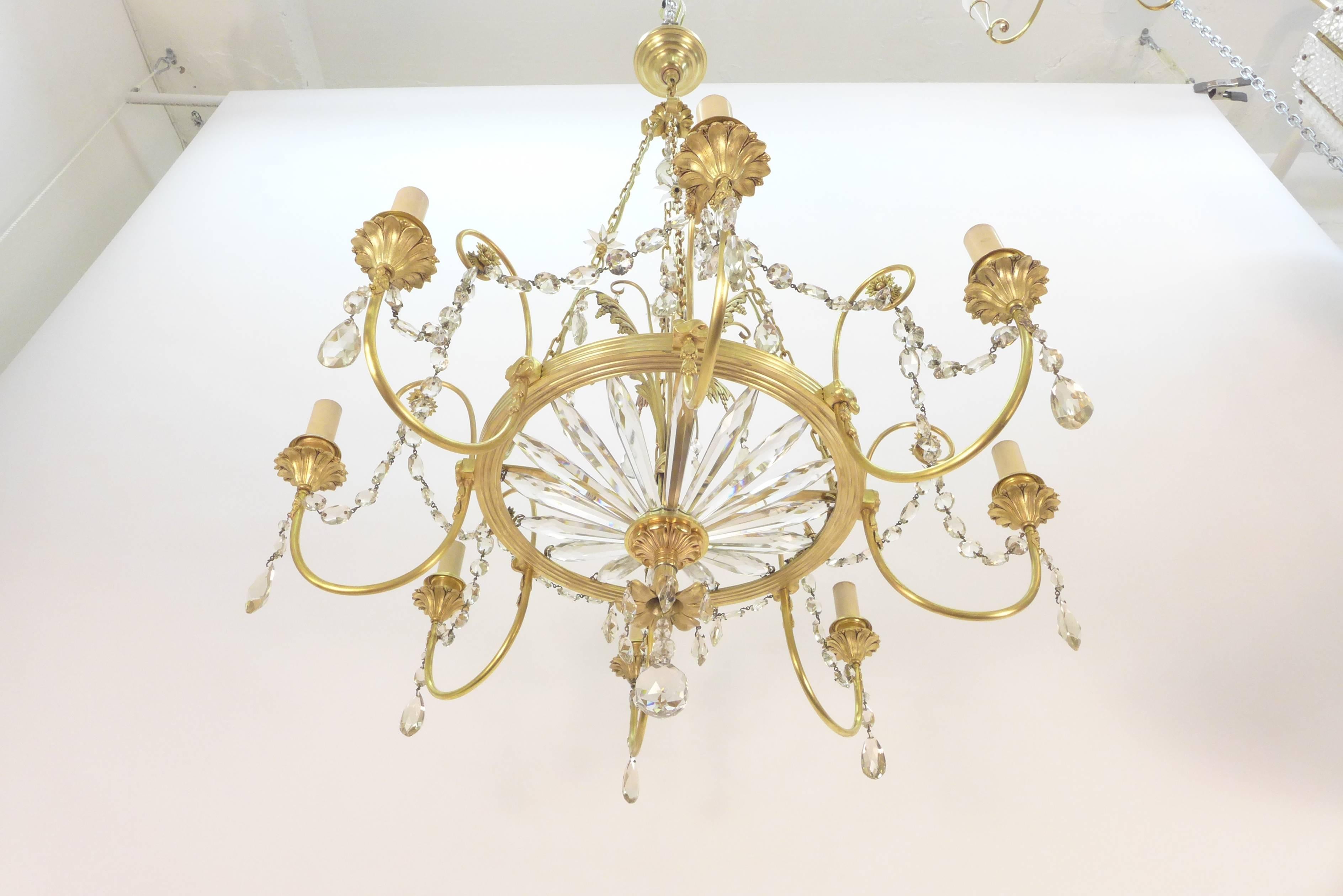 A French gilt bronze and glass eight-light chandelier late 19th century.
The linked hanging chains descending to a circlet issuing scroll branches with foliate-cast drip pans and sconces hung with faceted drops, a basket of faceted glass