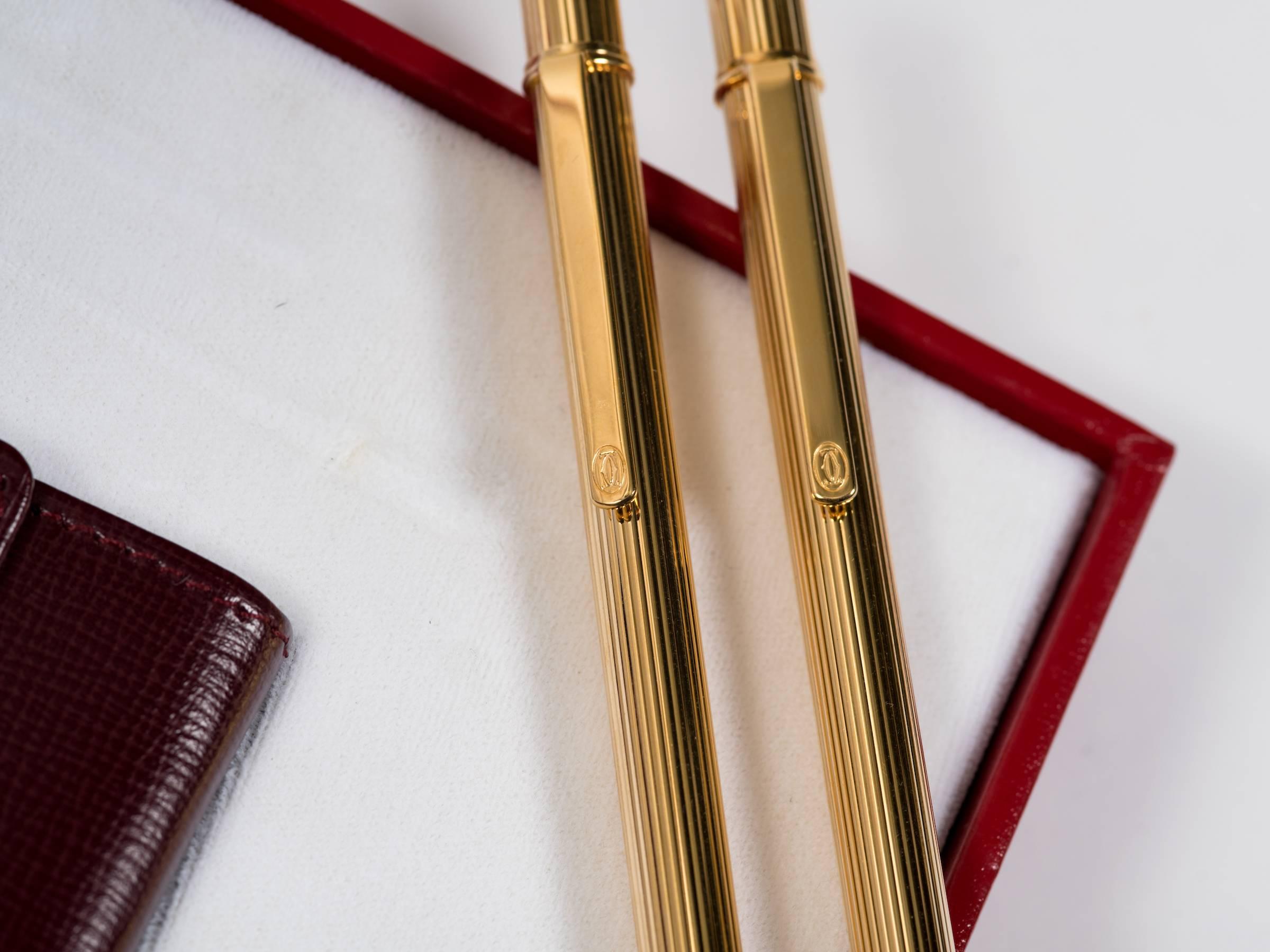 Parure de stylos et de crayons Cartier avec porte-monnaie en cuir.