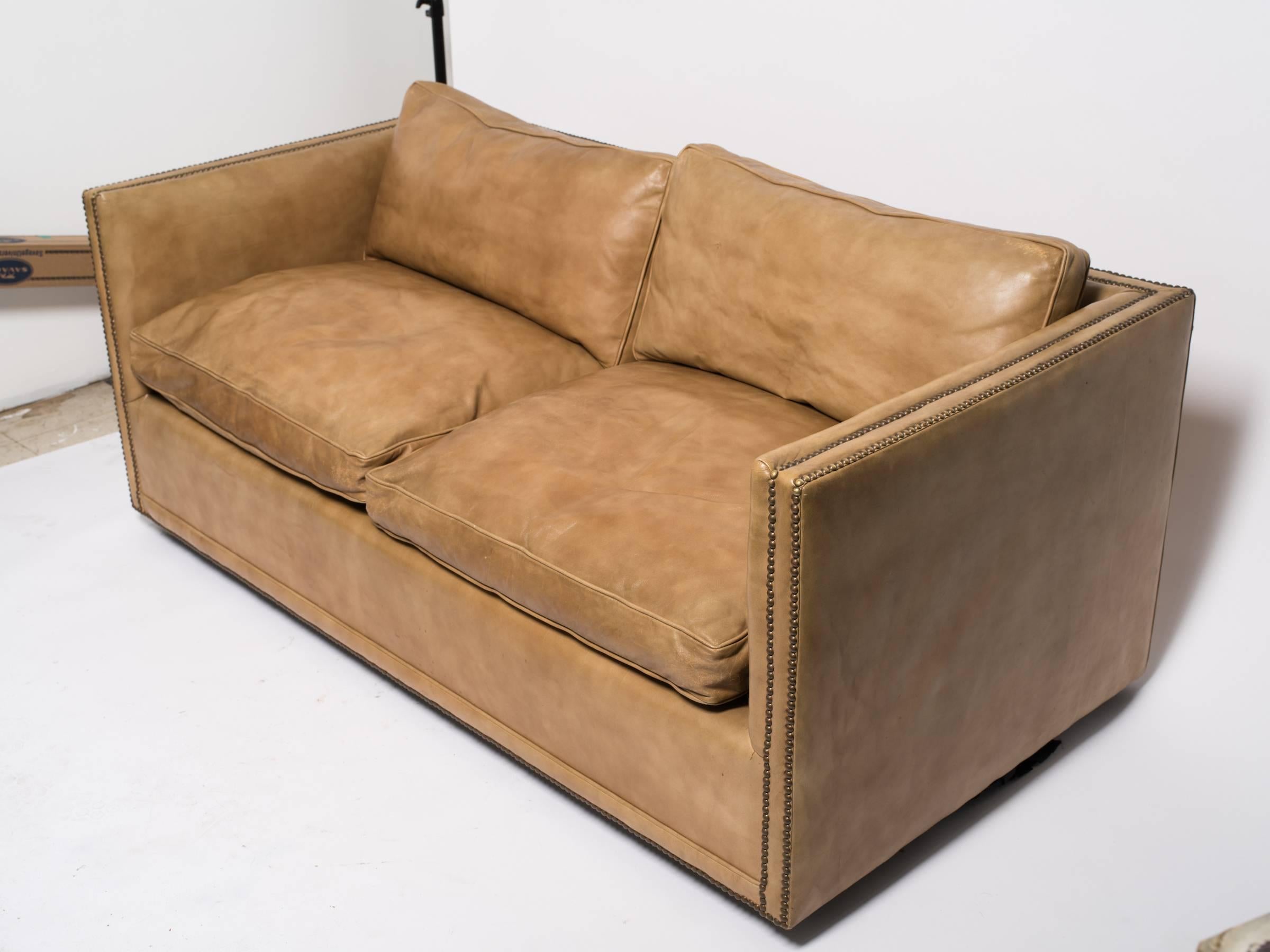 1970s down filled leather nailhead cube settee.

There is a small tear below the cushion that needs to be glued down.