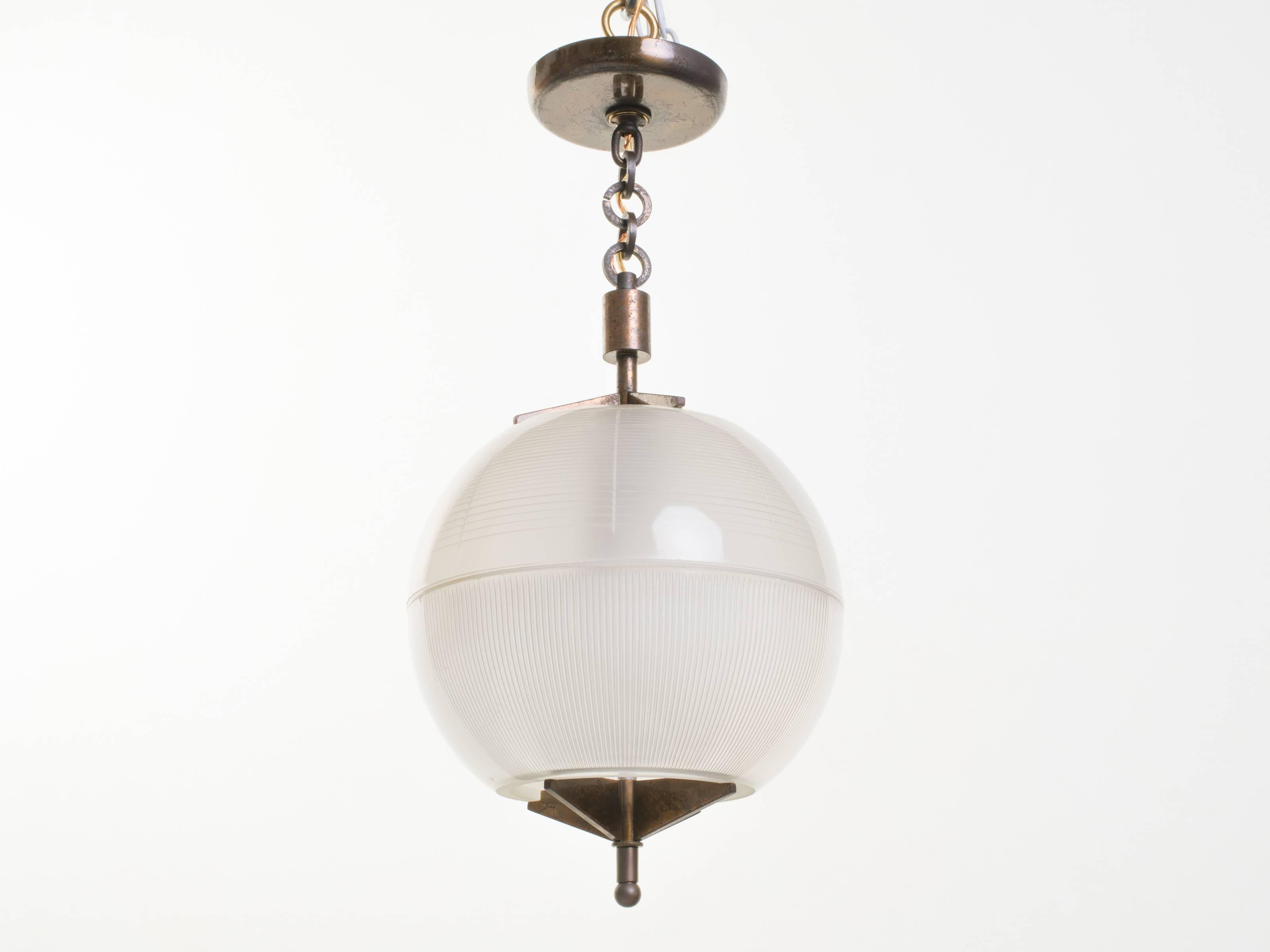 Vintage pendant light with a clear glass sphere and a X-shaped patinated brass base.