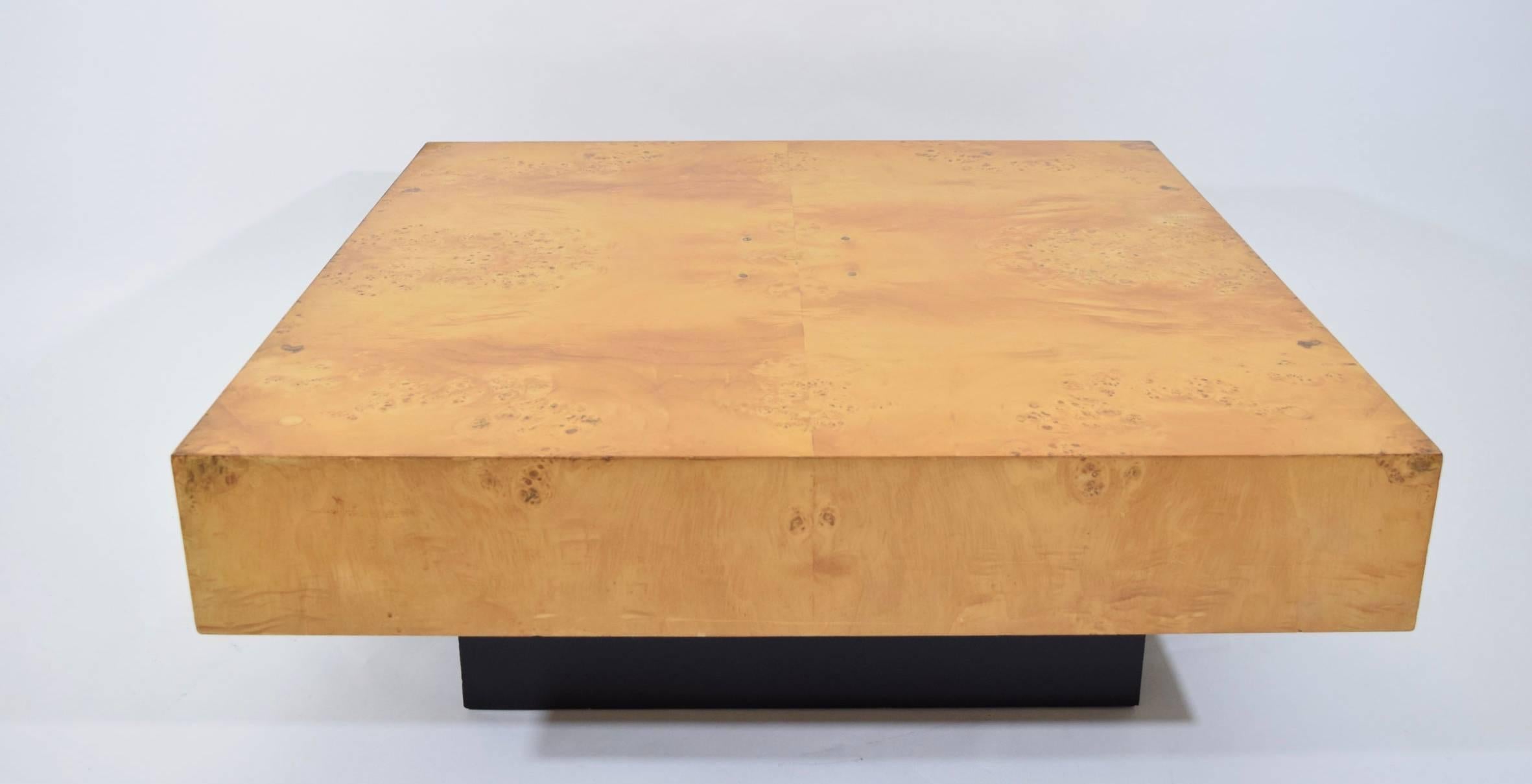 Solid burl wood coffee table on black base by Milo Baughman.