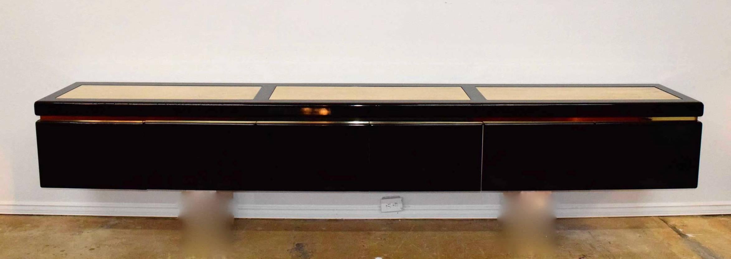 Custom-made in the 1990s. Black lacquer with brass trim and inlaid travertine. Six doors in total, conceal four pull-out drawers (one is missing in the photo but we have located) and shelf storage. Plenty of good storage. Travertine is in very nice