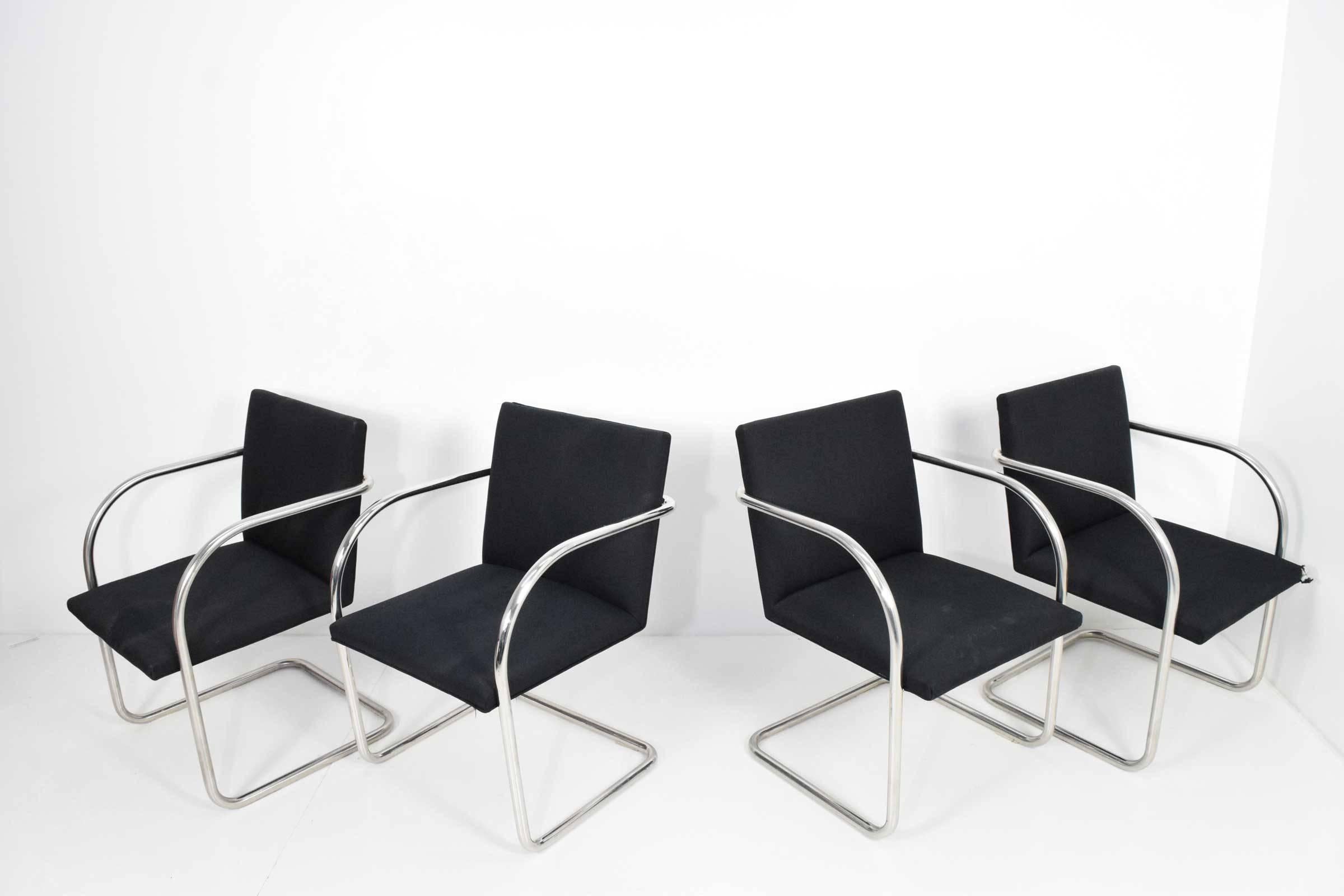Set of four Brno chairs by Knoll designed by Mies van der Rohe. Chairs are in fabric which has wear and it is recommended they be re-upholstered. Frames are shiny polished stainless steel so better quality than chrome-plated version.