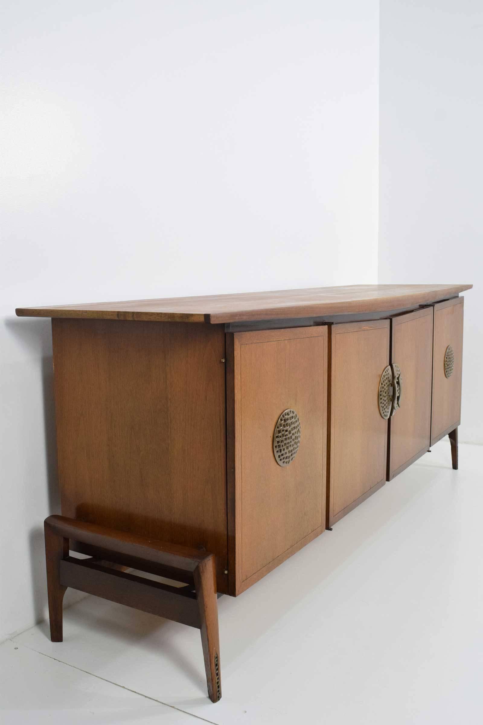 Walnut with brushed gold metal detail on legs and handles. Very well constructed with shelves in center and drawers on each side. Floats on a wooden base.