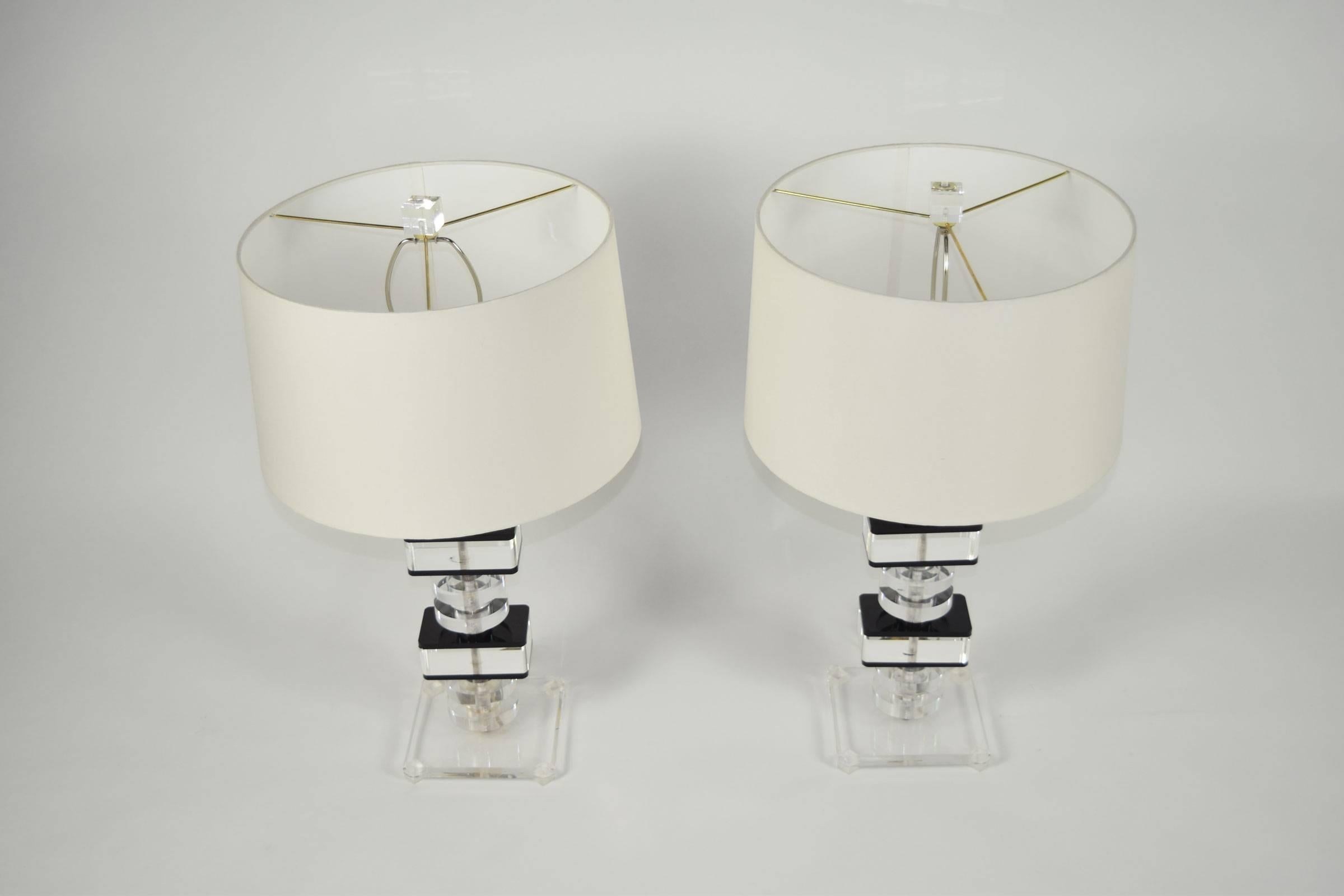 Pair of Mid Century stacked lucite table lamps made in France. Lamps are accented with black lucite overlay on large lucite squares. Accented with new lucite finials.