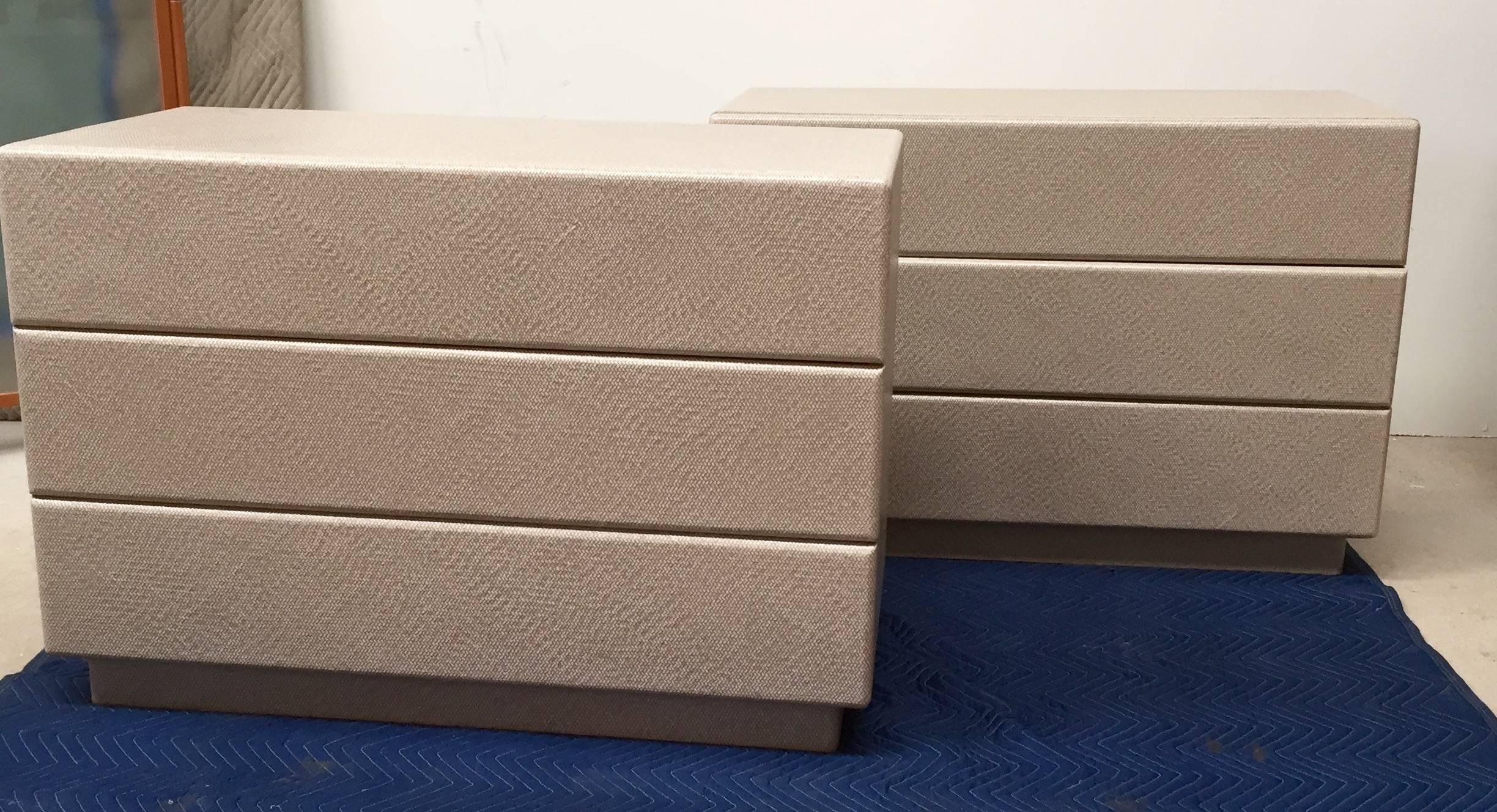 With their modernist, clean design, these chests are in the style of Karl Springer. They are clad in a taupe textured linen and rest on a recessed plinth base.