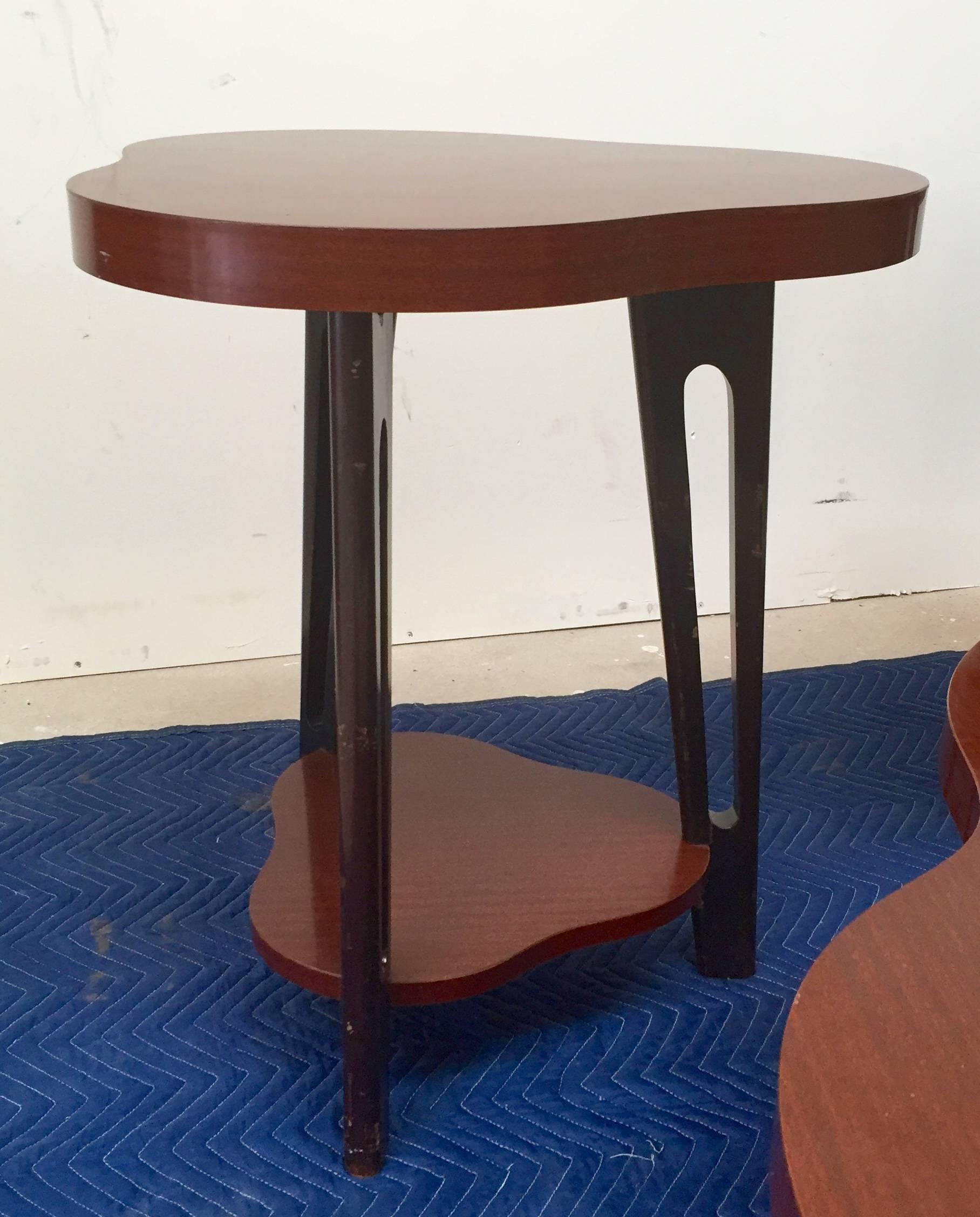 Early 1950s design set of tables. Original wood grain laminate tops set on stylized wooden hairpin shaped legs in black.
The dimensions on these tables is as follows:
Side tables: 27 1/2" tall x 19" to 22" in diameter.
Cocktail