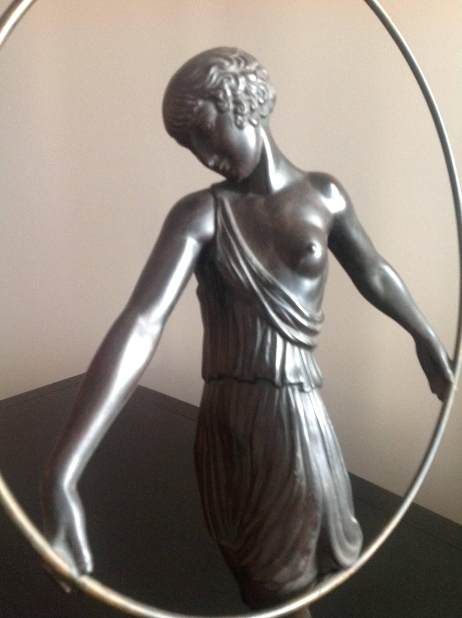 This Art Deco bronze with a marble base captures a lithe young woman dancing with a hoop. It is French bronze with a dark green patina and mounted on a black marble base.

It is by 