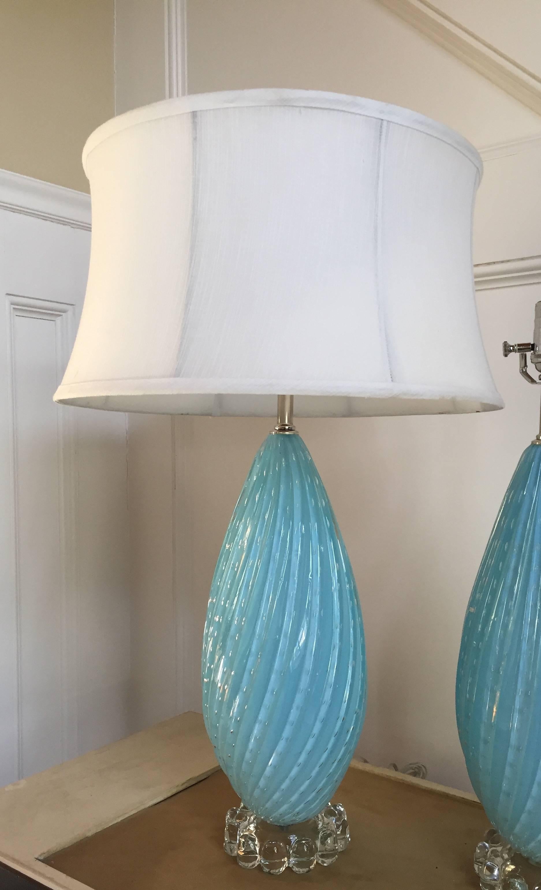 The Classic teardrop shape of these lamps is accentuated by gracefully swirling ribs accentuated by clear oval shapes within the glass. They have been newly rewired with nickel fittings and a dimmer switch, and are mounted on clear glass bases of