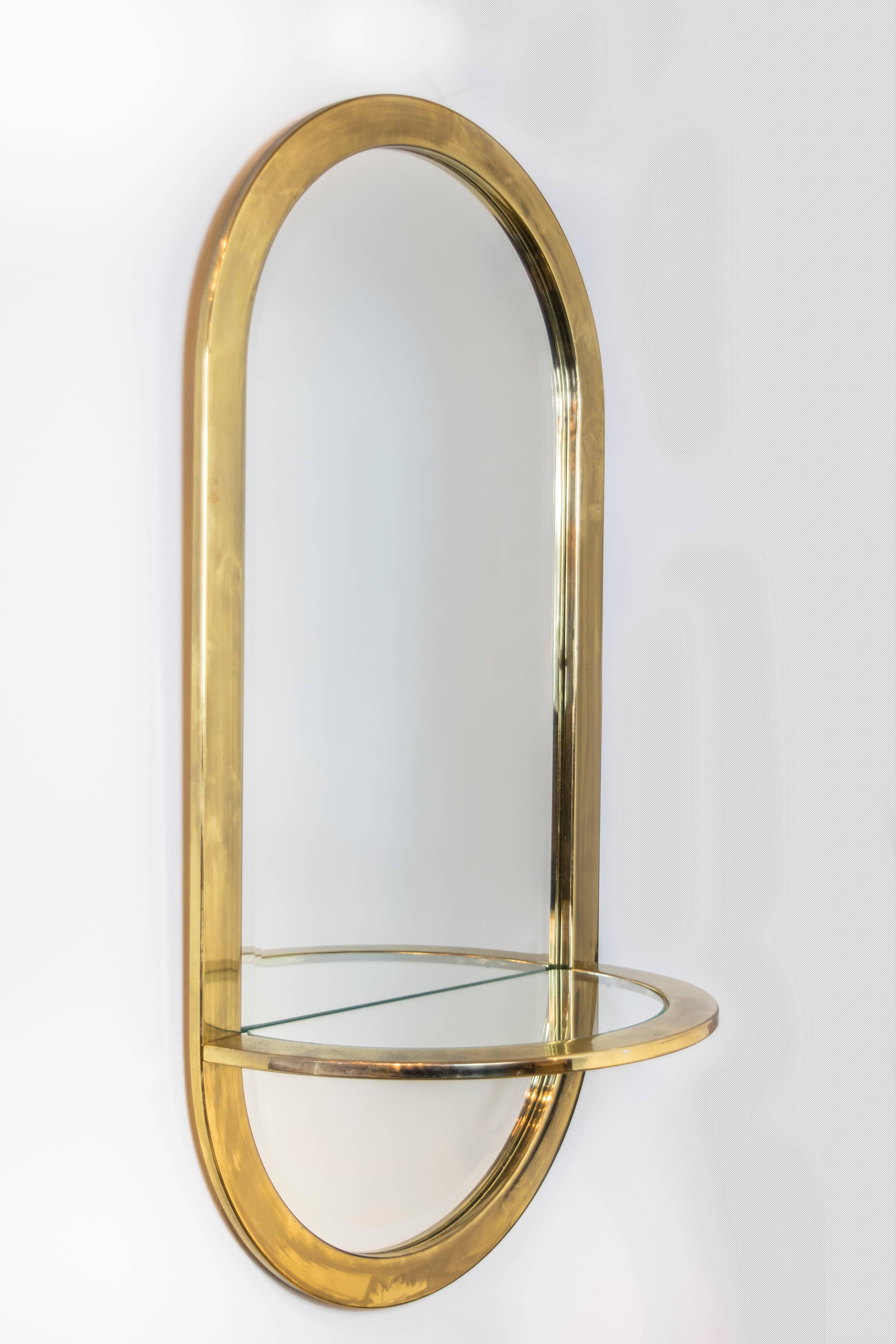 Classic late 1960s or early 1970s design by DIA, this brass-plated mirror has beveled edges and a glass shelf, perfect for a powder room or entry hall.
