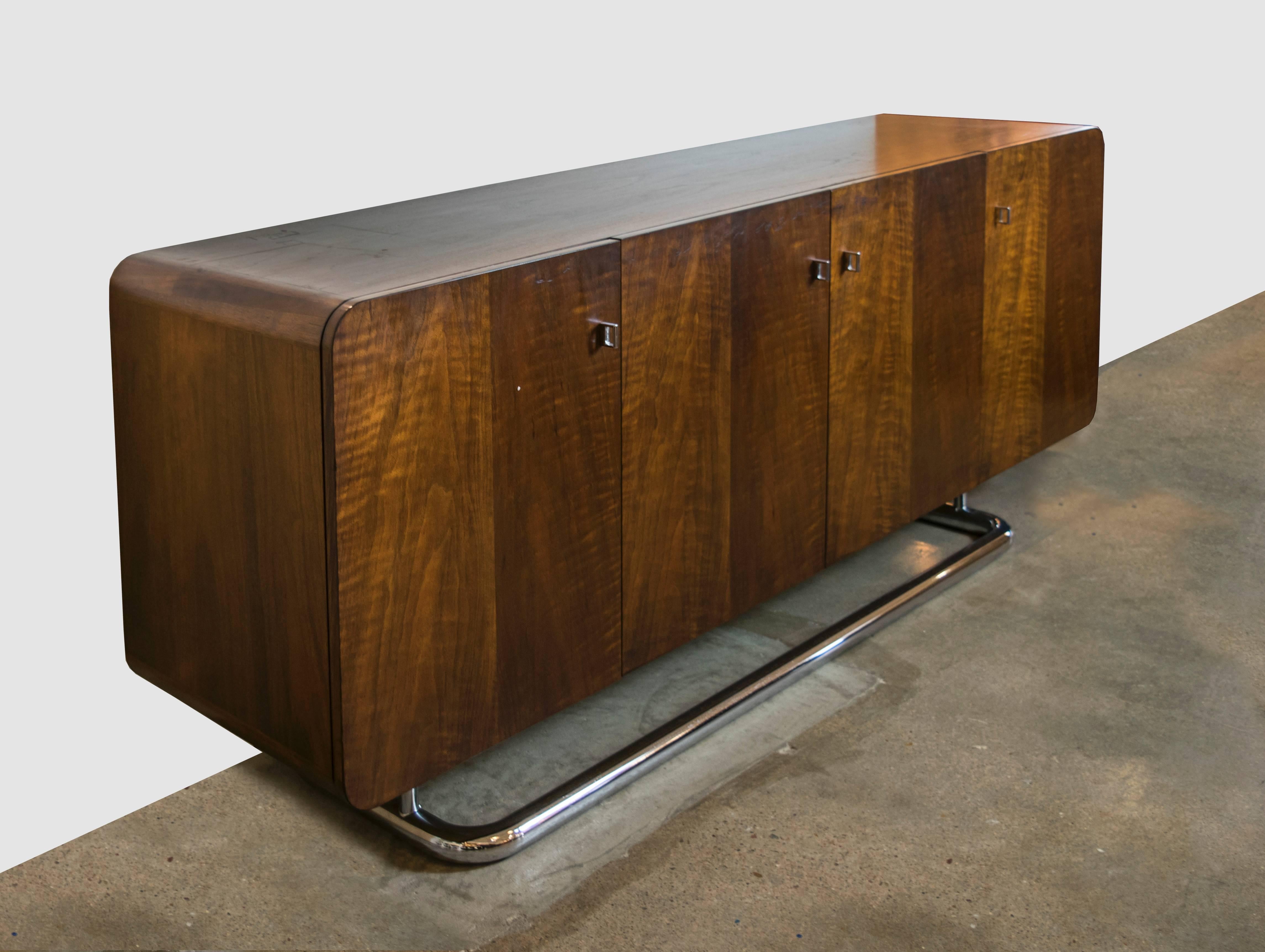 An early 1970s Thomasville credenza in a stunning black walnut with dramatic grain patterning. Rounded edges soften the look of the cabinet and its situated on top of a recessed cantilevered rounded chrome base. With chrome finger pulls and is