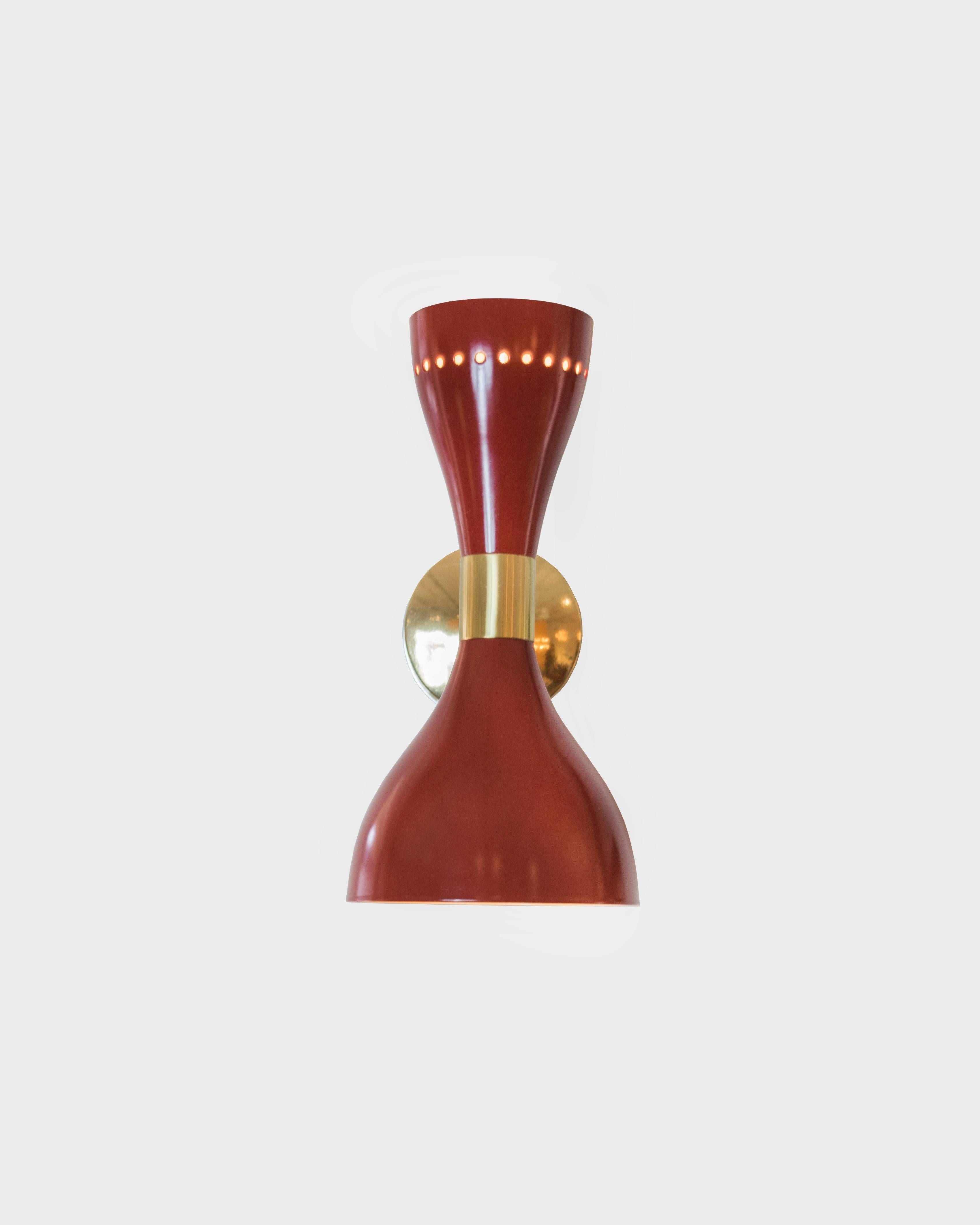 A pair of Stilnovo red lacquer and brass sconces with both up and down lighting in a conical shape. The outer rim extends 11.5 inches from the wall and the upper cone has a ring of perforated circles to add more drama to the pair.