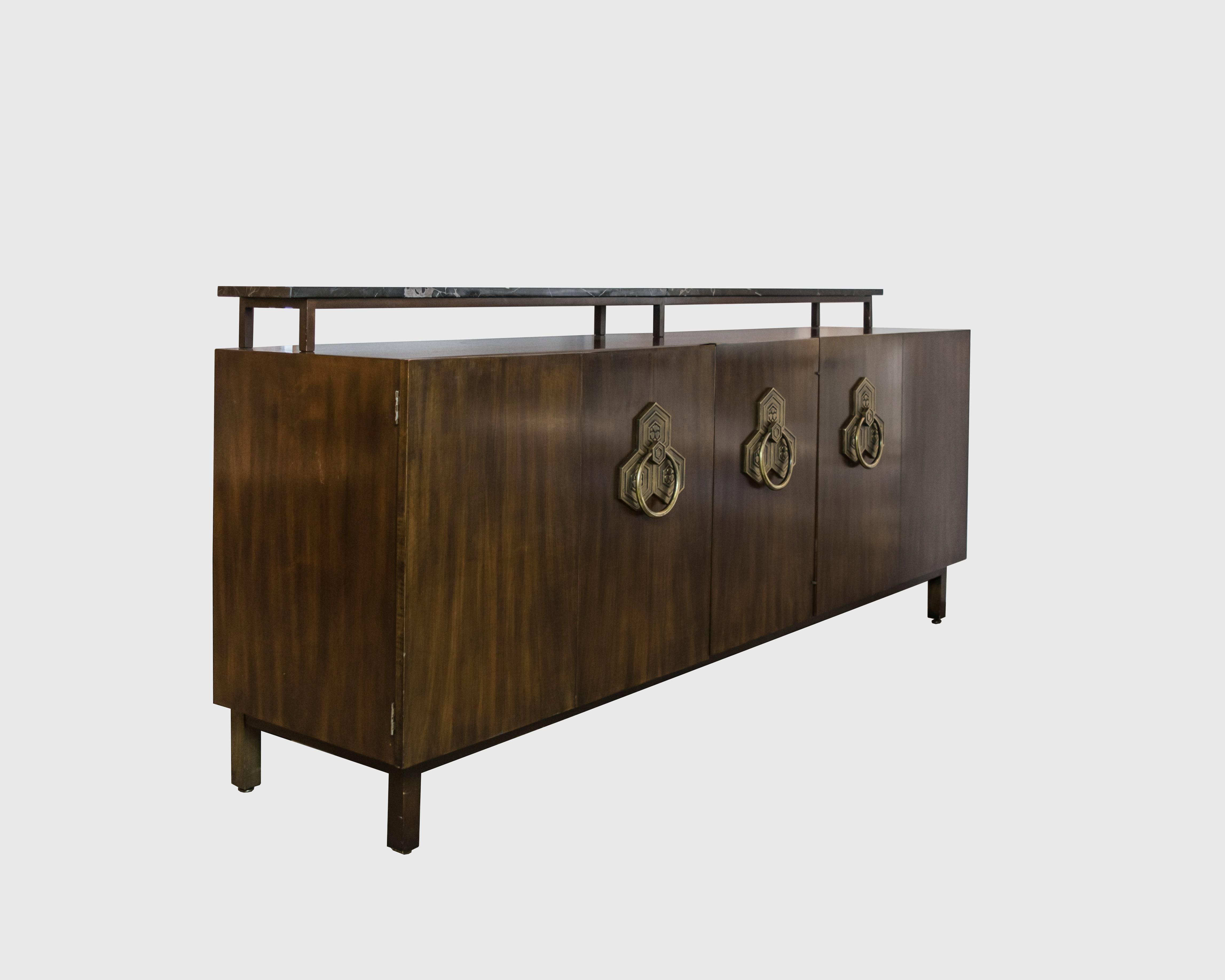 An absolutely elegant credenza by the master Robsjohn-Gibbings. Extra long with 5 panel front and intricate yet large brass hardware. We are not sure if the top marble piece is original to the console. It appears to have been added at some point so